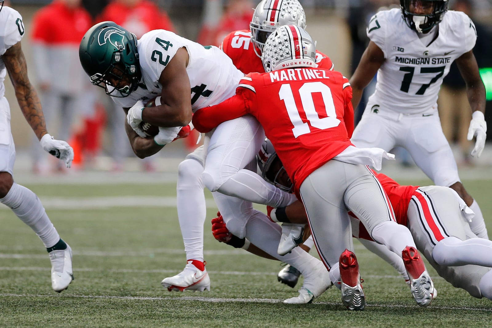 Ohio State defensive back Cameron Martinez, right, and linebacker Craig Young, center, tackle Michigan State running back Elijah Collins during the second half of an NCAA college football game Saturday, Nov. 20, 2021, in Columbus, Ohio. (AP Photo/Jay LaPrete)