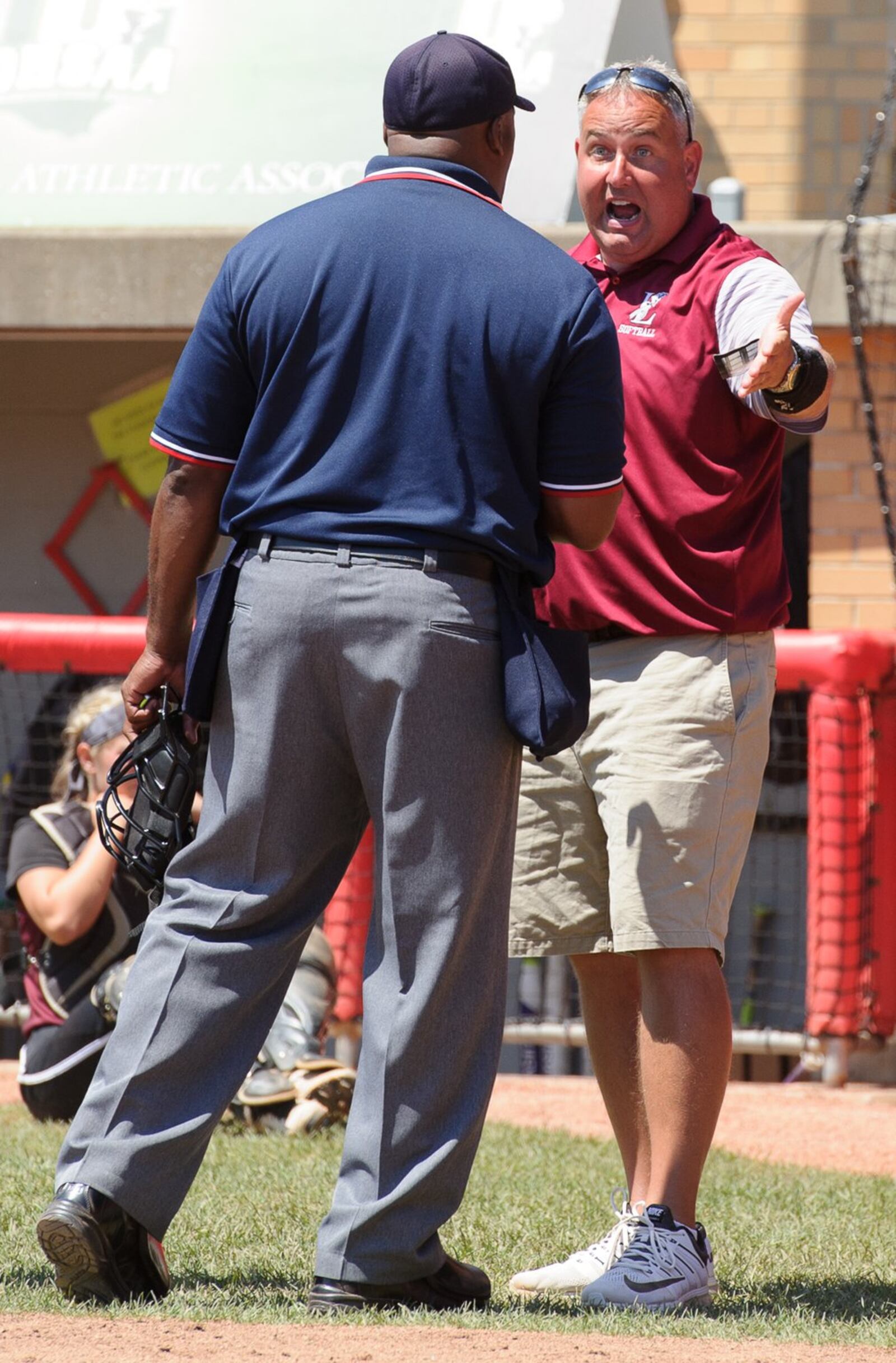 Lebanon coach Brian Kindell (right) argues with home-plate umpire Mike Burwell after Elyria scored the winning runs in the Division I state final on Saturday at Firestone Stadium in Akron. CONTRIBUTED PHOTO BY BRYANT BILLING