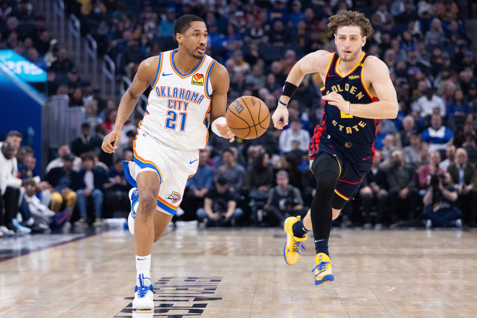 Oklahoma City Thunder guard Aaron Wiggins (21) dribbles past Golden State Warriors guard Brandin Podziemski during the first half of an NBA basketball game Wednesday, Jan. 29, 2025, in San Francisco. (AP Photo/Benjamin Fanjoy)