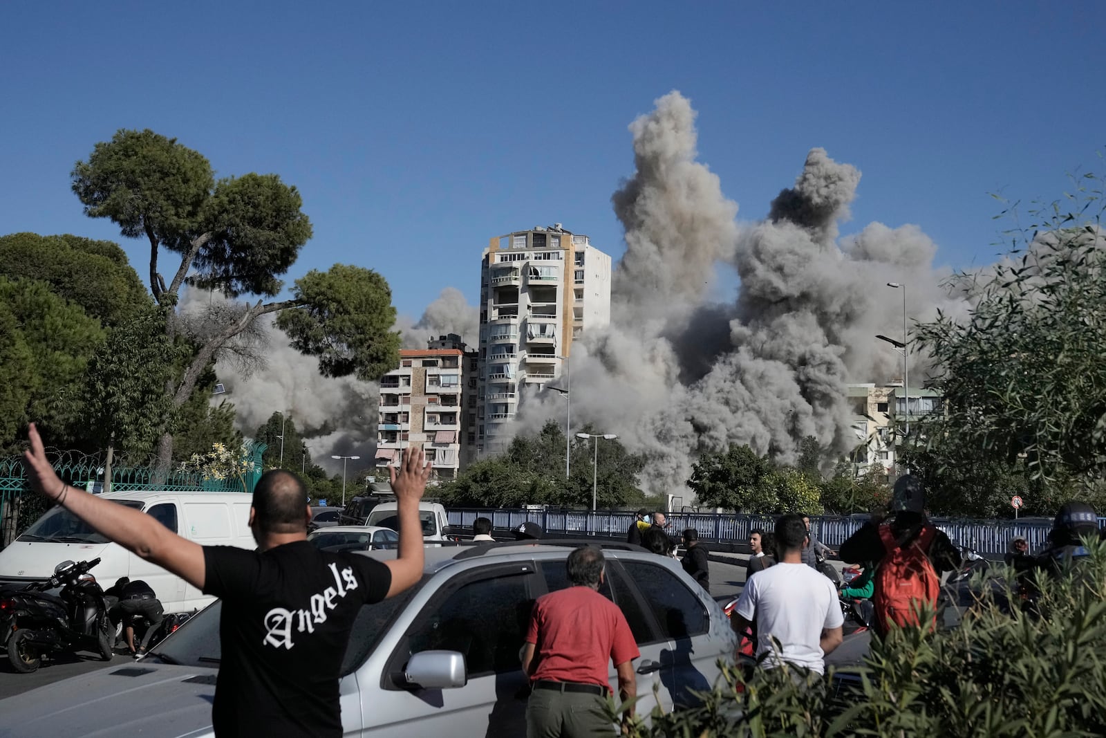 People react as smoke rises from a building that was hit by an Israeli missile in Ghobeiri, Beirut, Lebanon, Tuesday, Oct. 22, 2024. (AP Photo/Bilal Hussein)