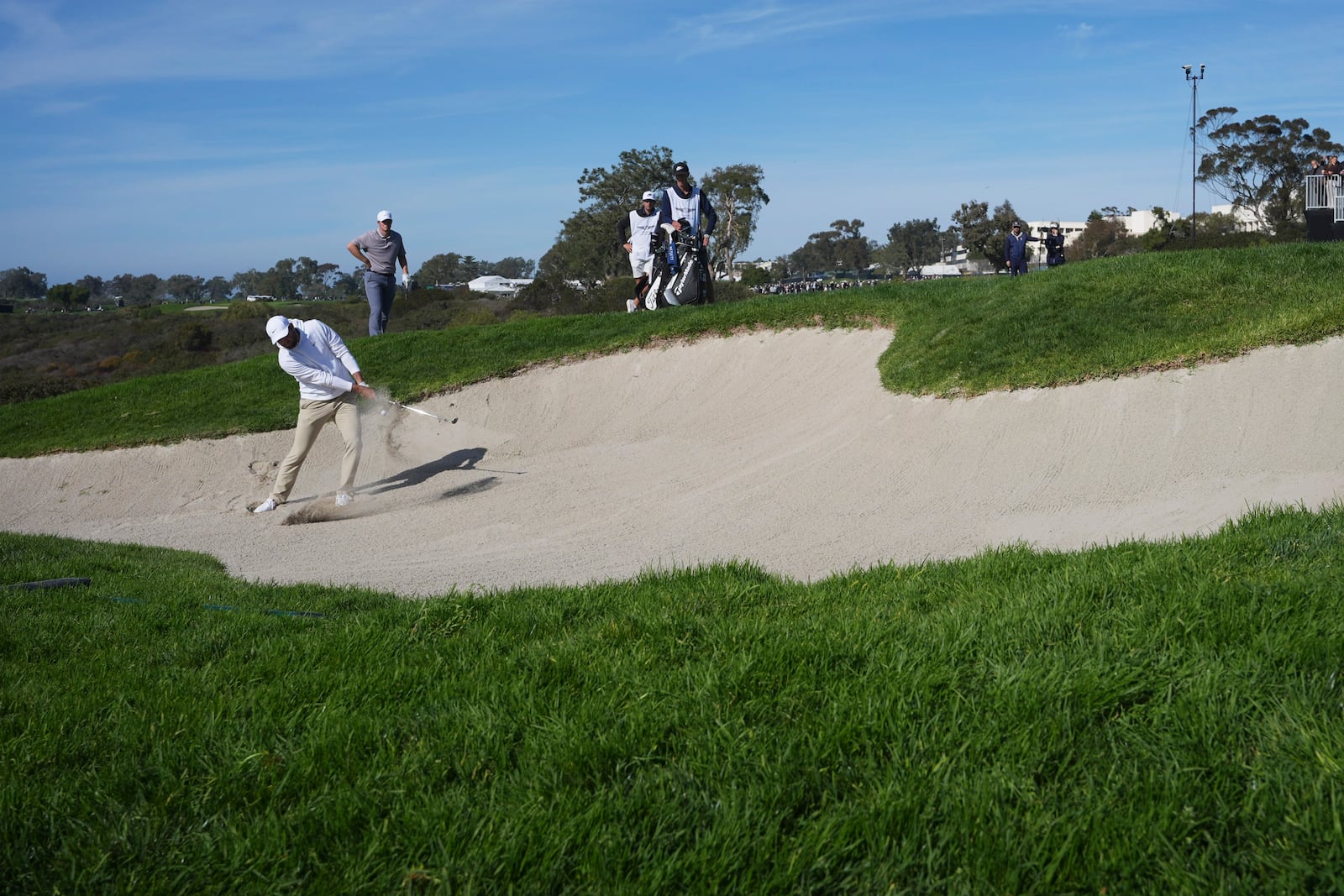 Scottie Scheffler hits out of a bunker on the 13th hole of the South Course at Torrey Pines during the third round of the Genesis Invitational golf tournament Saturday, Feb. 15, 2025, in San Diego. (AP Photo/Gregory Bull)