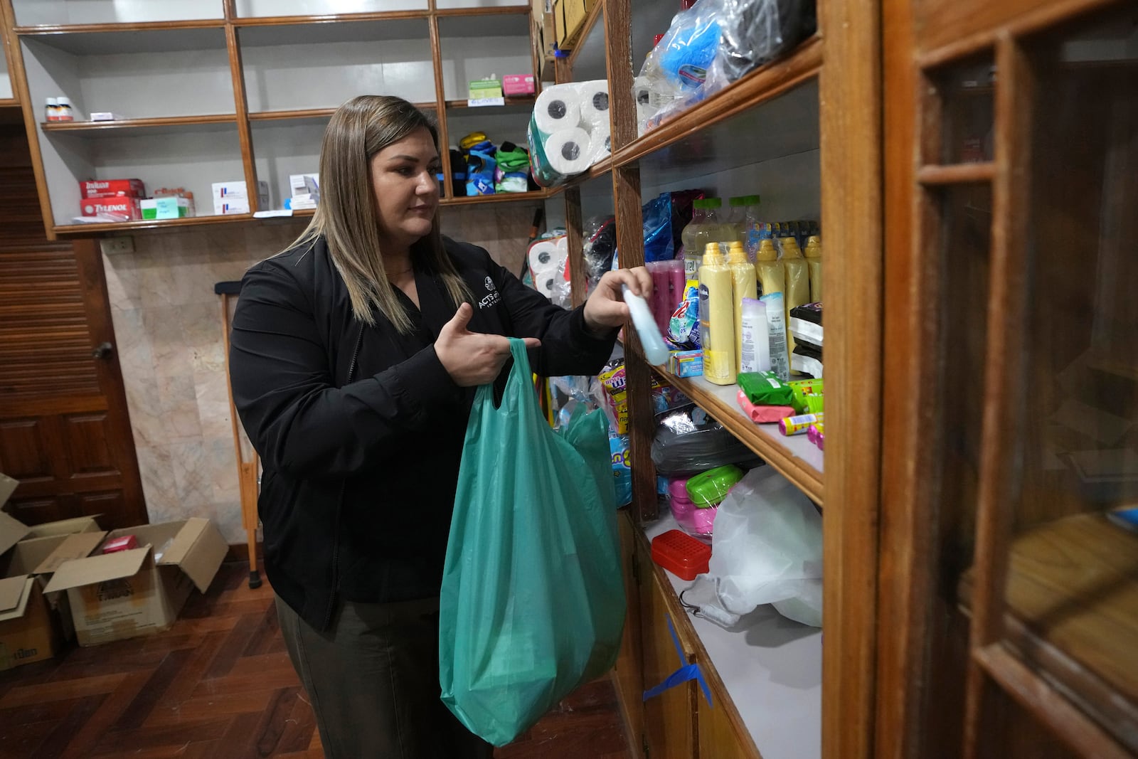 Amy Miller, Southeast Asia director of aid group Acts of Mercy International, collects shampoo supplies into a bag in Mae Sot, Thailand Wednesday, Feb. 26, 2025. (AP Photo/Sakchai Lalit)