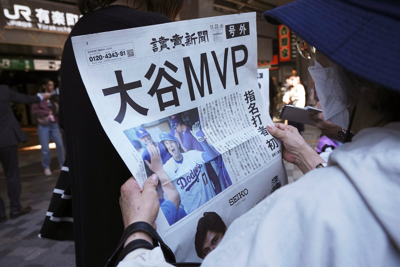 A person reads an extra edition of the Yomiuri Shimbun newspaper reporting that Los Angeles Dodgers' Shohei Ohtani won his third Most Valuable Player award, Friday, Nov. 22, 2024, in Tokyo. (AP Photo/Eugene Hoshiko)