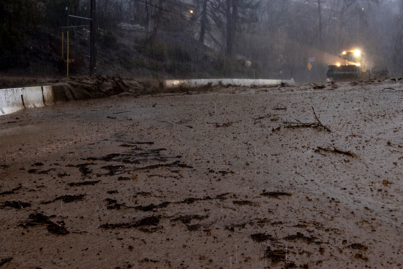 Mud is cleared from a road in the Eaton Fire zone during a storm Thursday, Feb. 13, 2025, in Altadena, Calif. (AP Photo/Etienne Laurent)