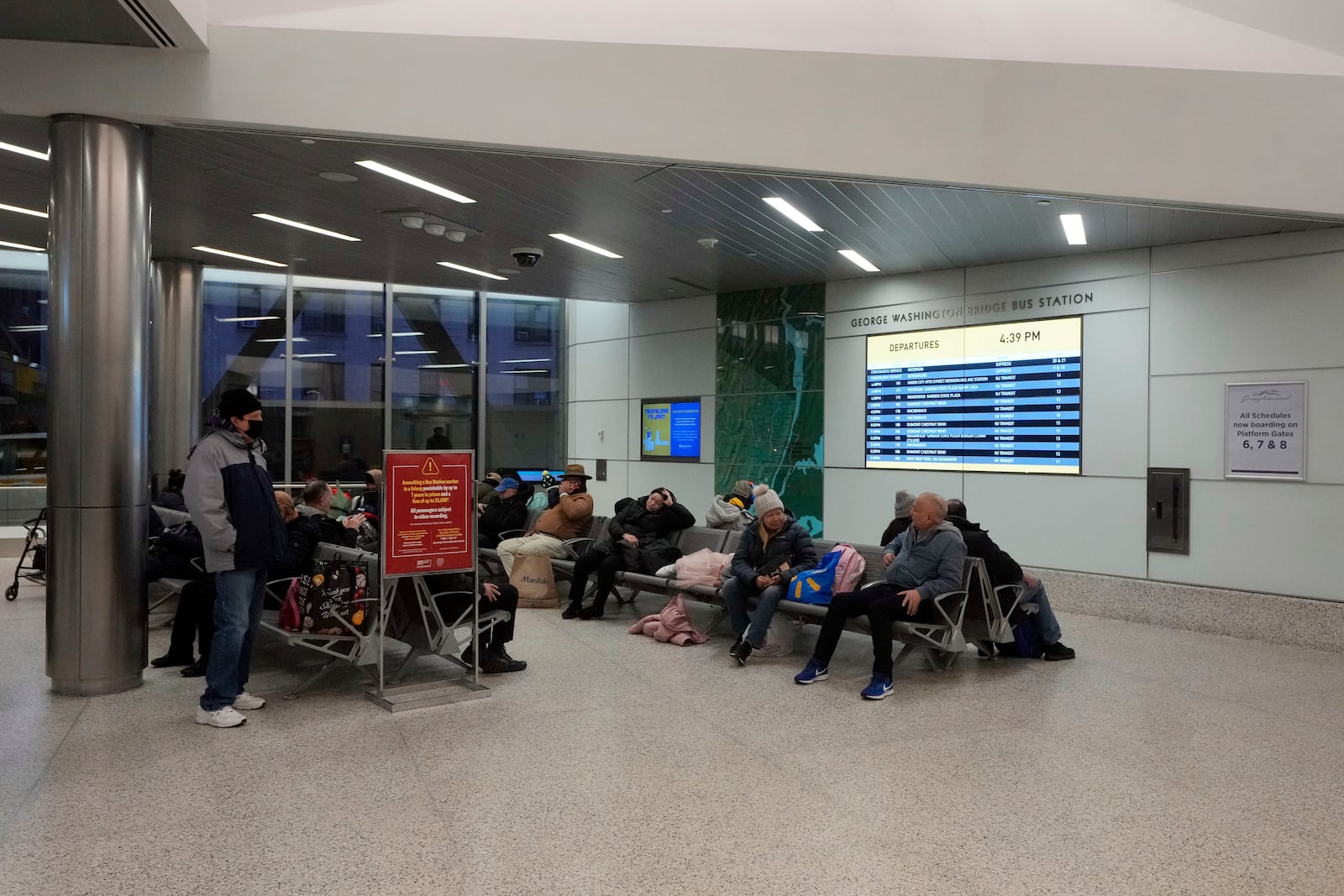 Commuters wait inside the George Washington Bridge Bus Station in New York, Friday, Dec. 6, 2024, where the gunman fleeing Wednesday's shooting of UnitedHealthcare CEO Brian Thompson took a taxi to, according to surveillance video. (AP Photo/Richard Drew)