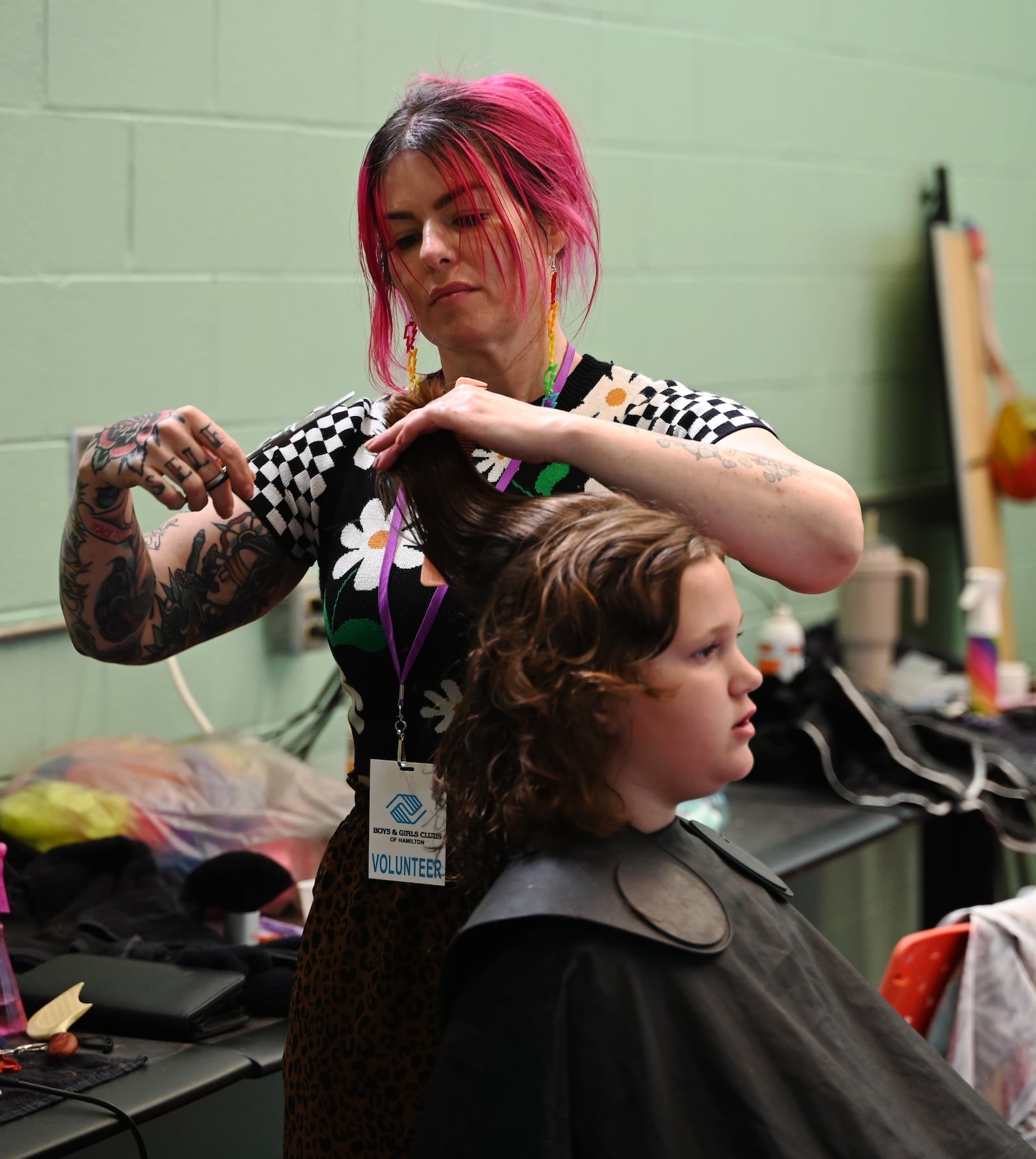 Biz Jarvis, owner of Hue Mane Salon in Hamilton, is giving back to the community when she offered free haircuts to the kids that attend the Boys and Girls Clubs of Hamilton on Grand Boulevard. She's pictured here giving a haircut to a girl at the Boys and Girls Club on Wednesday, July 31, 2024.  MICHAEL D. PITMAN/STAFF