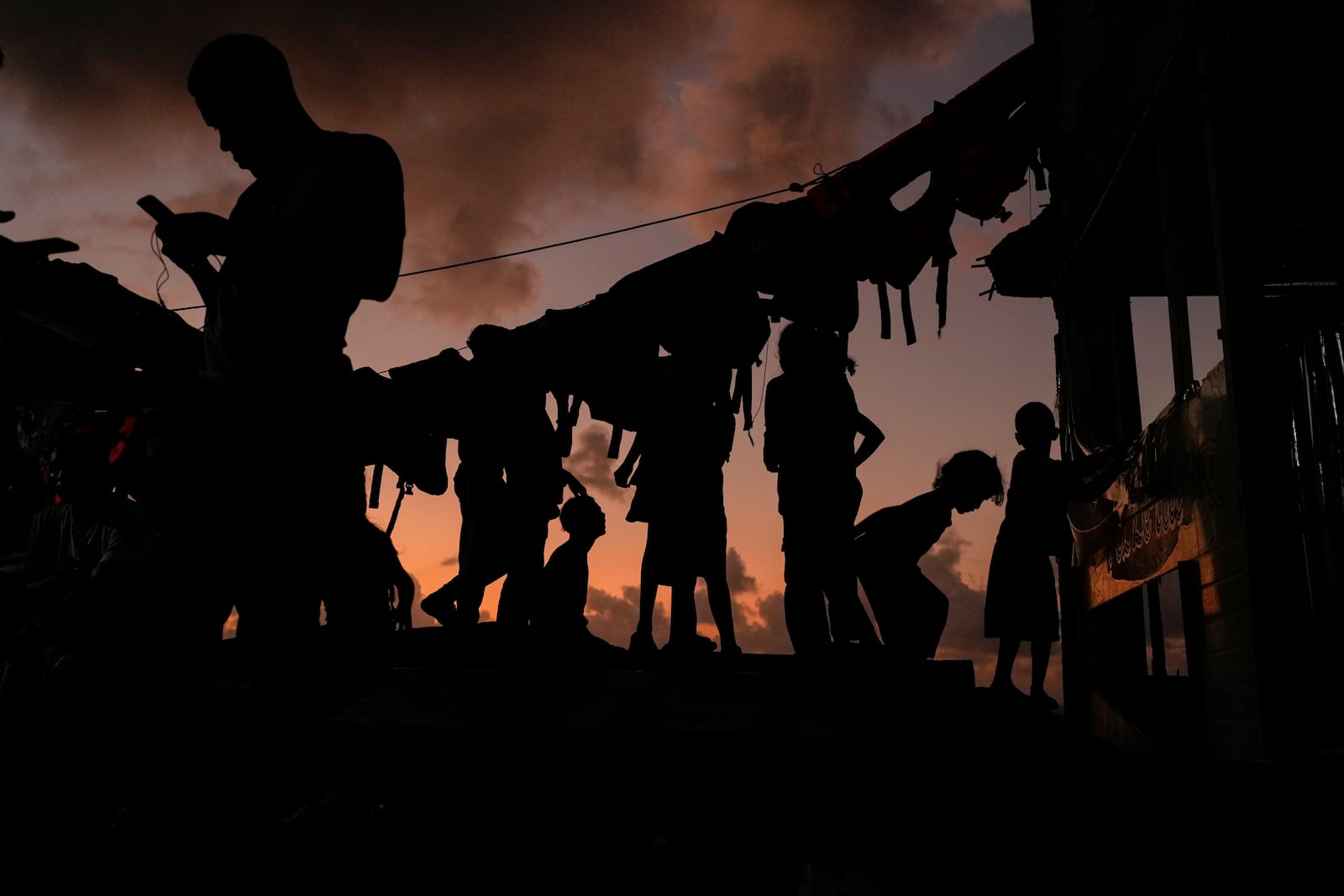 Migrants wind down during sunset on Gardi Sugdub island, on Panama's Caribbean coast, Sunday, Feb. 23, 2025. (AP Photo/Matias Delacroix)