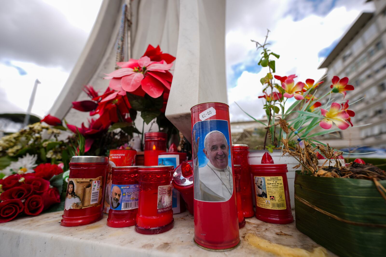 Candles, one showing a photo of Pope Francis, are seen in front of the Agostino Gemelli Polyclinic in Rome, Friday, Feb. 14, 2025, where Pope Francis has been hospitalized to undergo some necessary diagnostic tests and to continue his ongoing treatment for bronchitis. (AP Photo/Andrew Medichini)