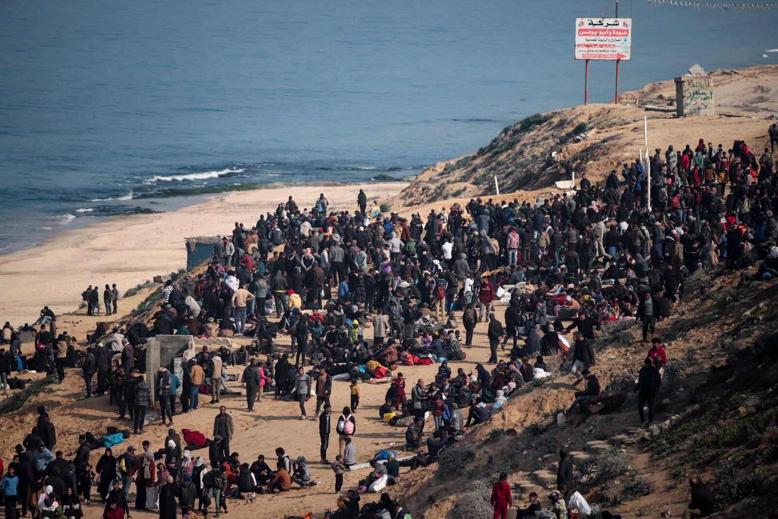 Displaced Palestinians gather with their belongings near a roadblock on the al Rashid Street, as they wait to return to their homes in the northern part of the Gaza Strip, Sunday, Jan. 26, 2025, days after the ceasefire deal between Israel and Hamas came into effect. (AP Photo/Jehad Alshrafi)