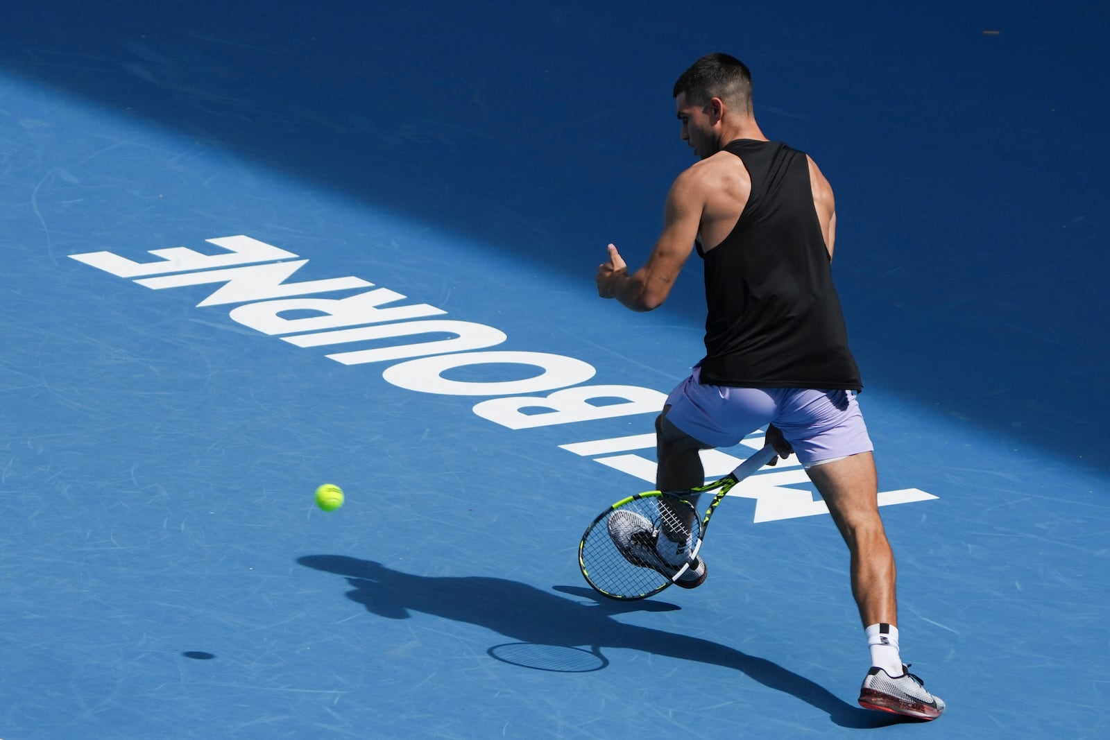 Spain's Carlos Alcaraz plays a shot between his legs during a practice session ahead of the Australian Open tennis championship in Melbourne, Australia, Thursday, Jan. 9, 2025. (AP Photo/Mark Baker)