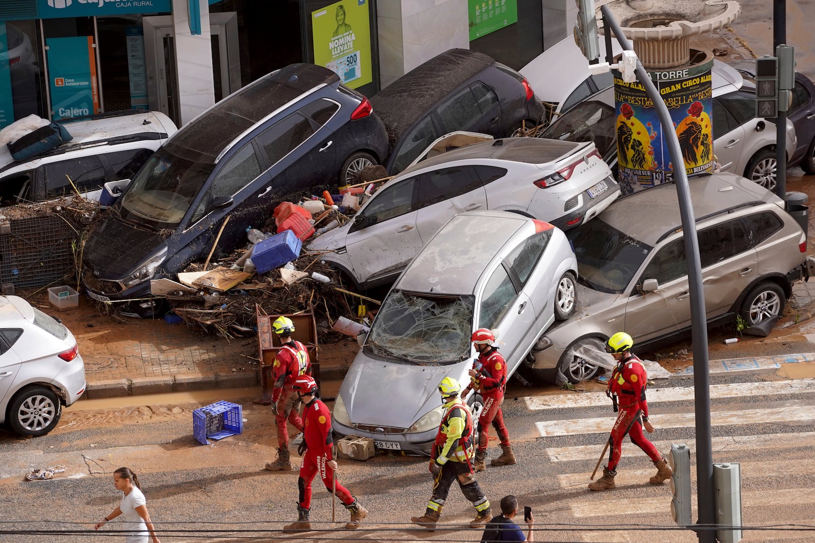 Emergency crew members walk past cars piled up after being swept away by floods in Valencia, Spain, Wednesday, Oct. 30, 2024. (AP Photo/Alberto Saiz)