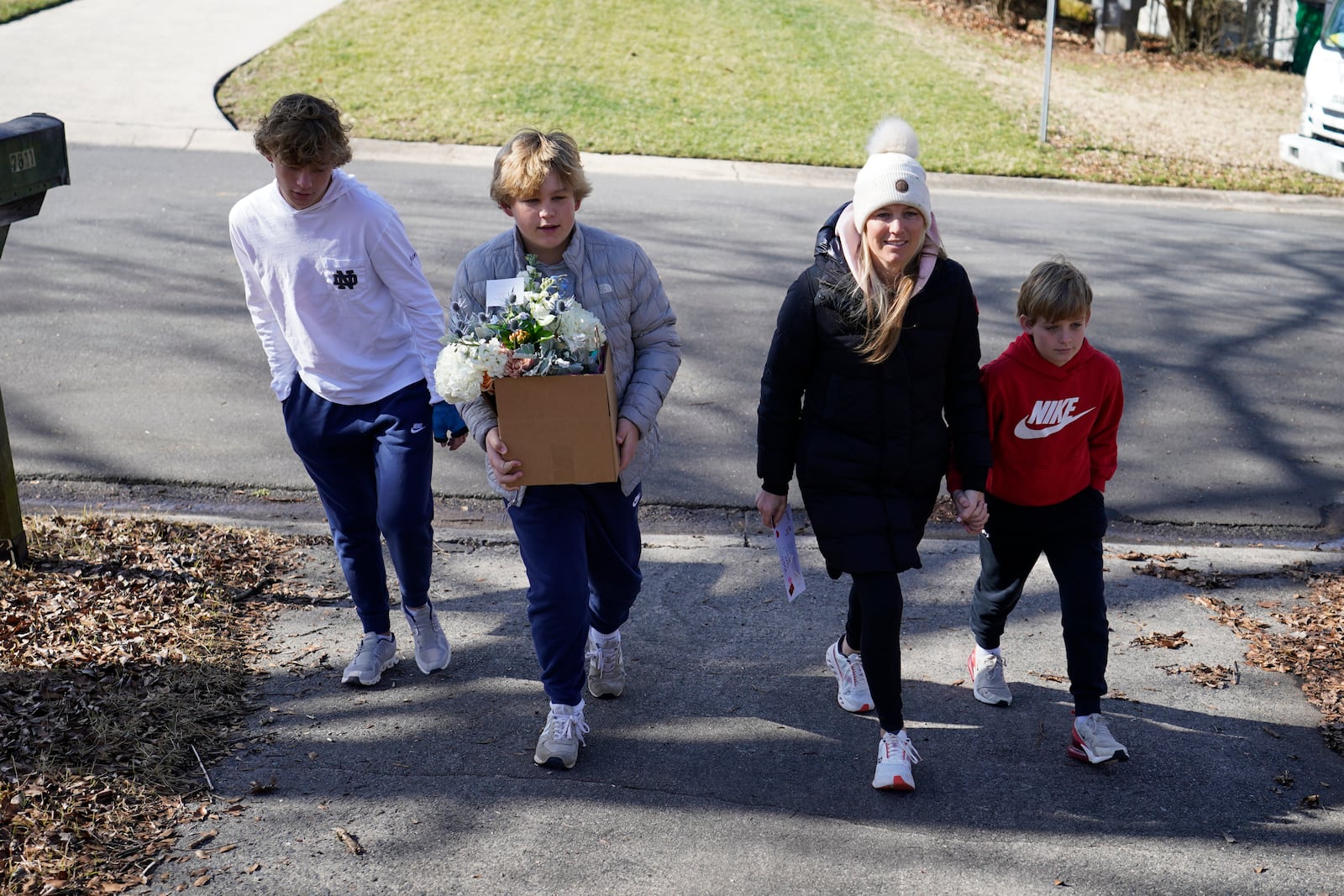 Kelly Lilly, third from left, with her children from left, Jack, 15, Henry, 13, and Luke, 10, deliver flowers to a Valentine's Day Widow Outreach Project recipient, Friday, Feb. 14, 2025, in Charlotte, N.C. (AP Photo/Erik Verduzco)