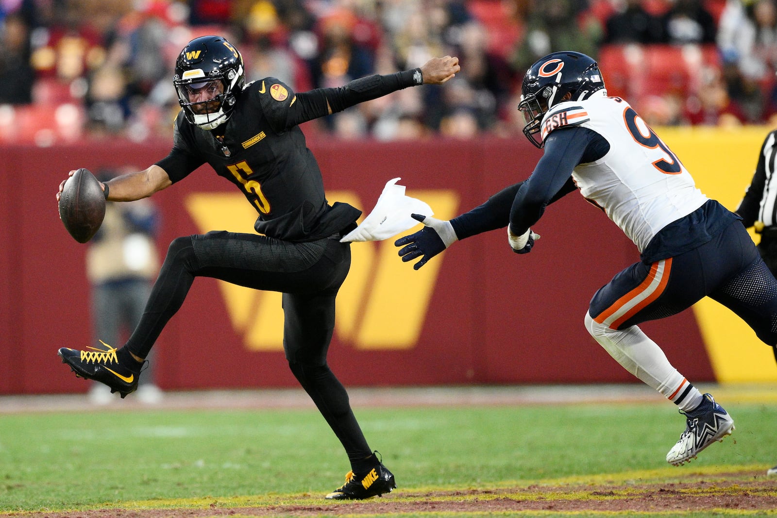 Washington Commanders quarterback Jayden Daniels (5) scrambles away from Chicago Bears defensive end Montez Sweat (98) in the second half of an NFL football game Sunday, Oct. 27, 2024, in Landover, Md. (AP Photo/Nick Wass)