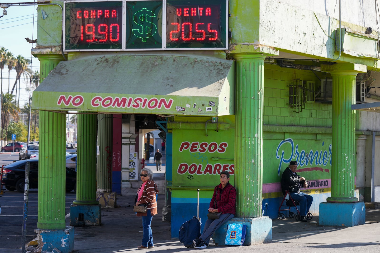 People wait for ground transportation near an exchange office in Mexicali, Mexico, Saturday, Feb. 1, 2025. (AP Photo/Fernando Llano)