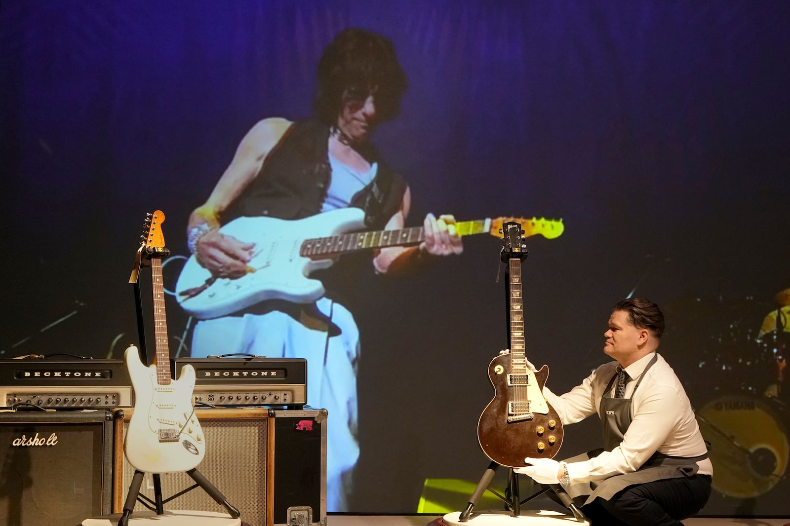 An art handler displays a displays a Gibson, Kalamazoo, Michigan, 1954 and 1972, a Solid-Body Electric Guitar, Les Paul, known as 'The Oxblood' at the Jeff Beck The Guitar Collection ahead of the pre-sale exhibition at Christie's auction rooms in London, Tuesday, Jan. 14, 2025. (AP Photo/Kirsty Wigglesworth)