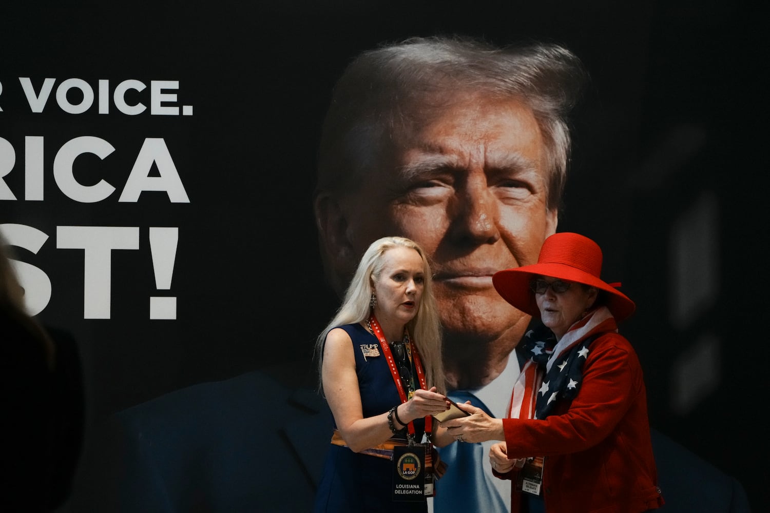 
                        Attendees stand in front of an image of former President Donald Trump, the Republican presidential nominee, on the third night of the Republican National Convention at the Fiserv Forum in Milwaukee, on Wednesday, July 17, 2024. (Hiroko Masuike/The New York Times)
                      