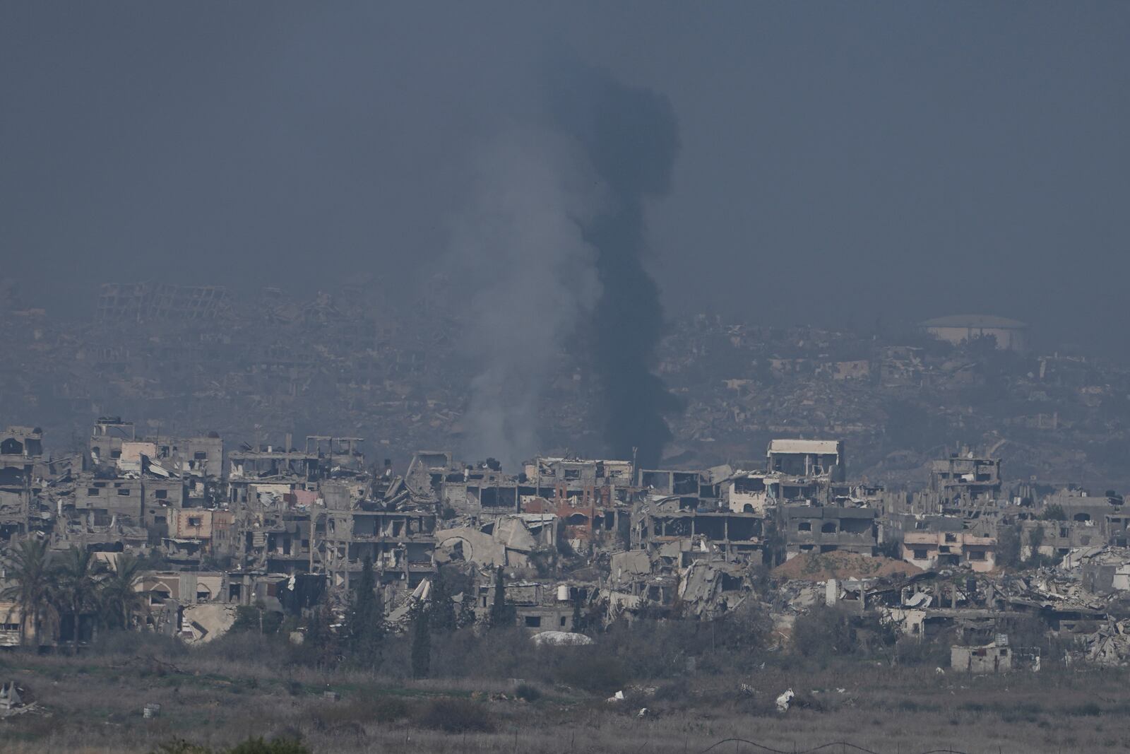 Smoke rises behind destroyed buildings by Israeli bombardments as seen inside the Gaza Strip from southern Israel, Thursday, Jan. 16, 2025. (AP Photo/Tsafrir Abayov)