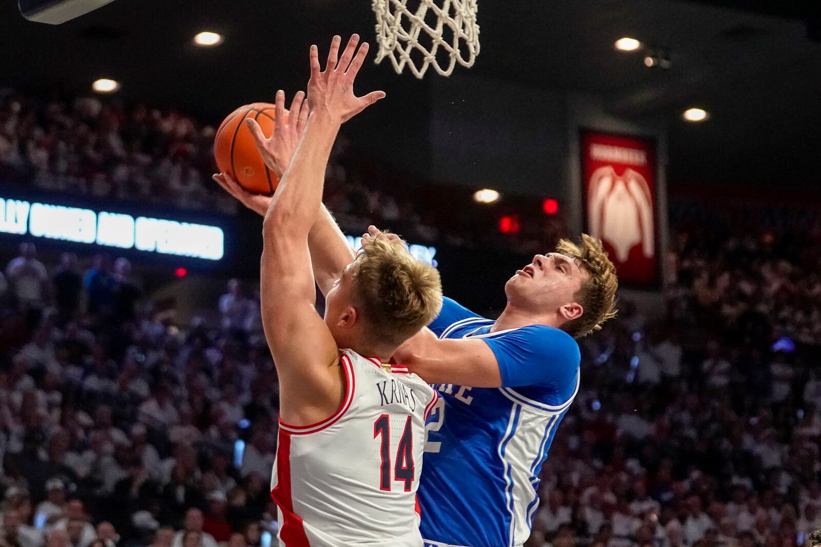 Duke guard Cooper Flagg, right, shoots around Arizona's Motiejus Krivas (14) during the first half of an NCAA college basketball game Friday, Nov. 22, 2024, in Tucson, Ariz. (AP Photo/Darryl Webb)