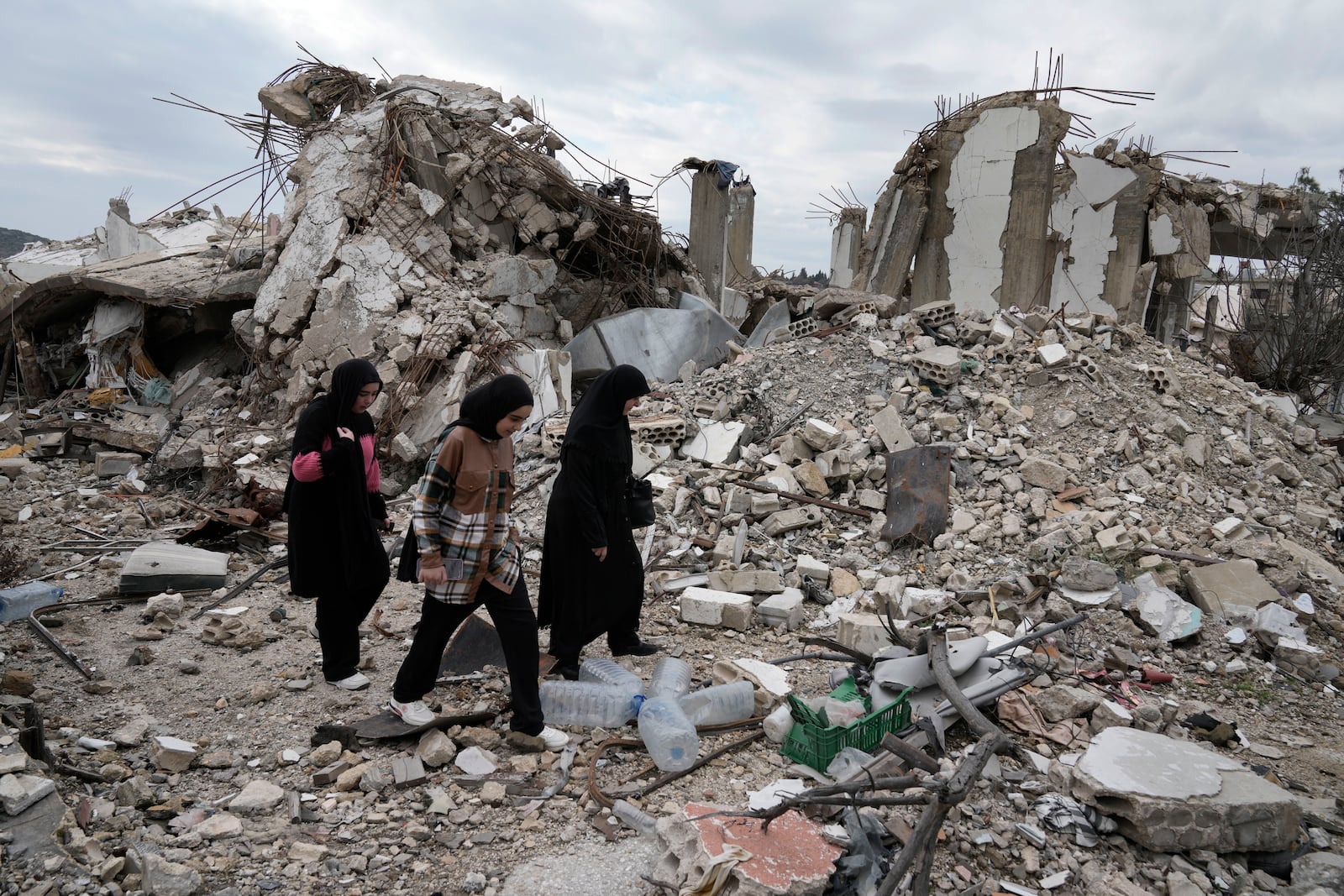 Lebanese citizens pass next to a destroyed house, as they check the destruction in their village caused by the Israeli air and ground offensive, in Aita al-Shaab, a Lebanese border village with Israel, south Lebanon, Sunday, Jan. 26, 2025. (AP Photo/Bilal Hussein)