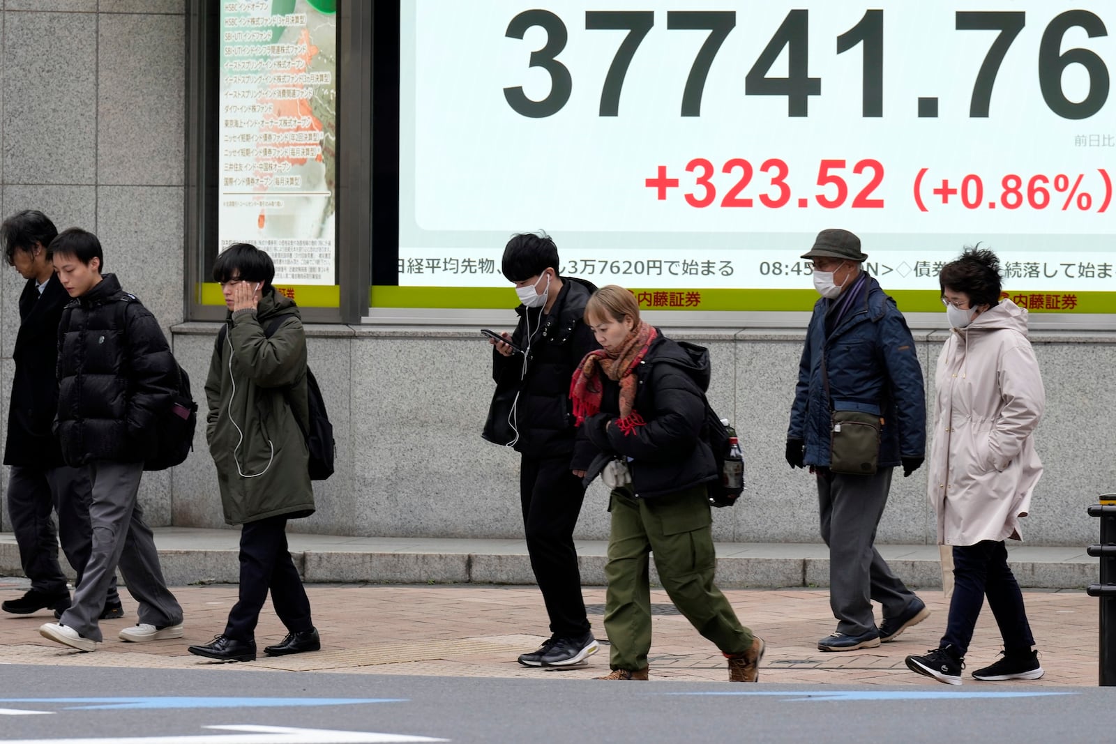 People walk in front of an electronic stock board showing Japan's Nikkei index at a securities firm Thursday, March 6, 2025, in Tokyo. (AP Photo/Eugene Hoshiko)