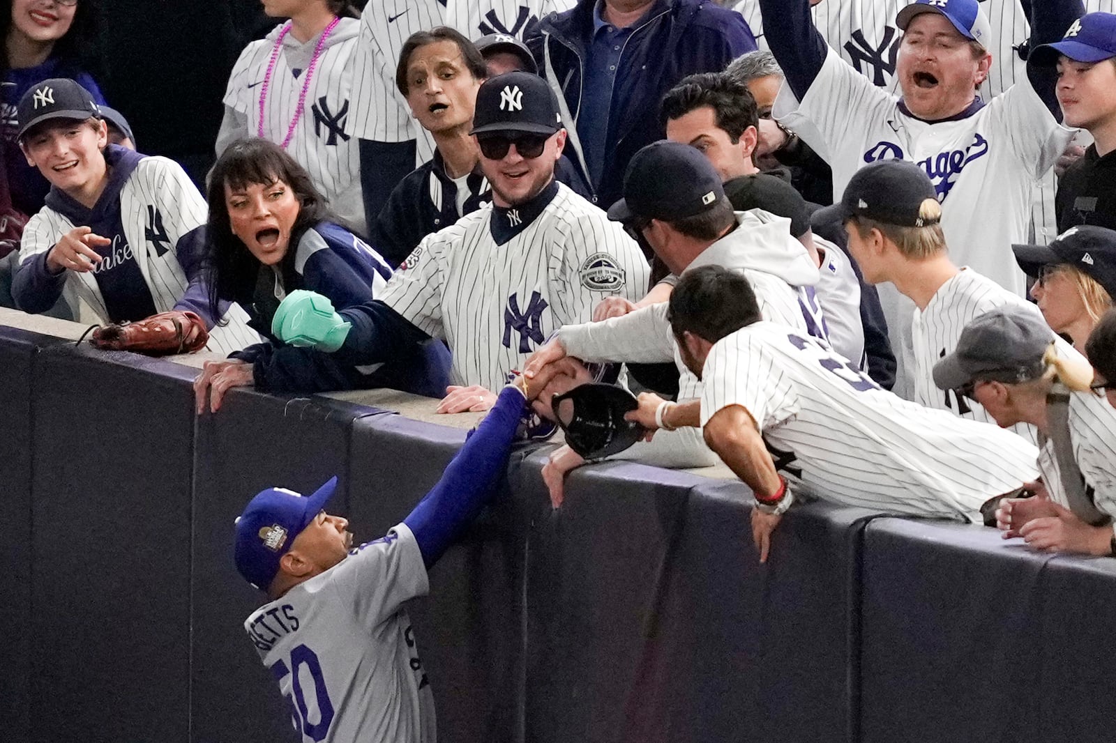 FILE - Fans interfere with a foul ball caught by Los Angeles Dodgers right fielder Mookie Betts during the first inning in Game 4 of the baseball World Series against the New York Yankees, Tuesday, Oct. 29, 2024, in New York. (AP Photo/Ashley Landis, File)