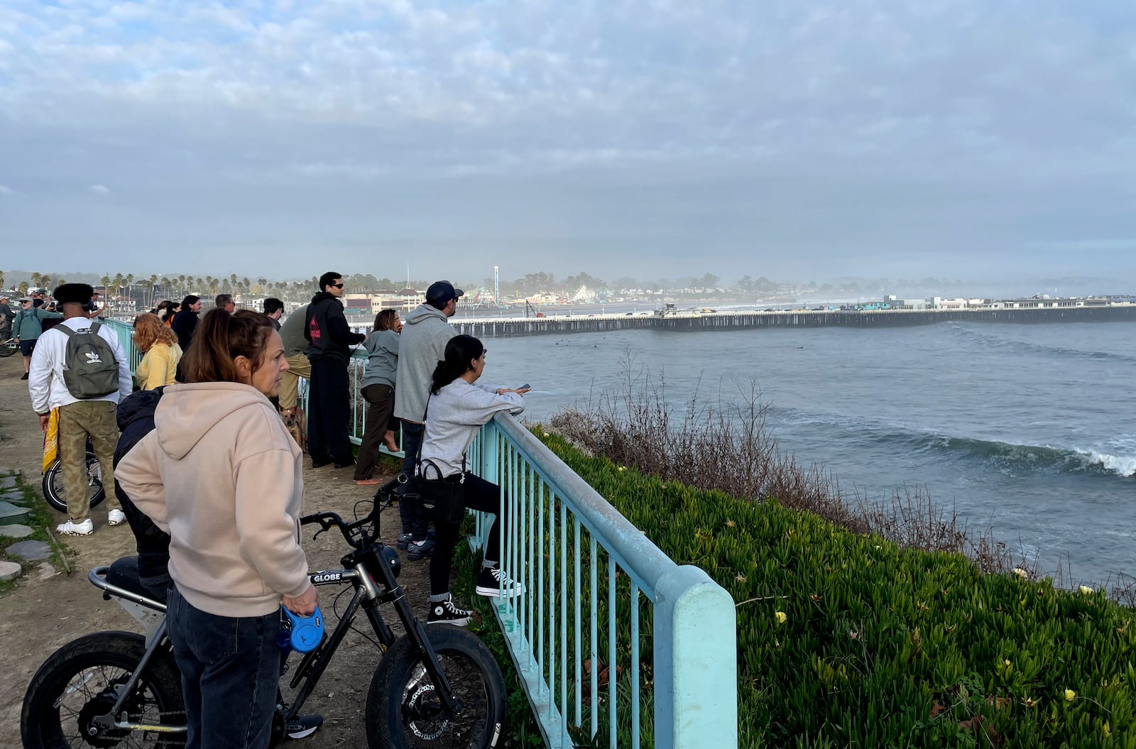 Spectators look out at a closed Santa Cruz wharf after the pier partially collapsed and fell into the ocean on Monday, Dec. 23, 2024, in Santa Cruz, Calif. (AP Photo/Martha Mendoza)