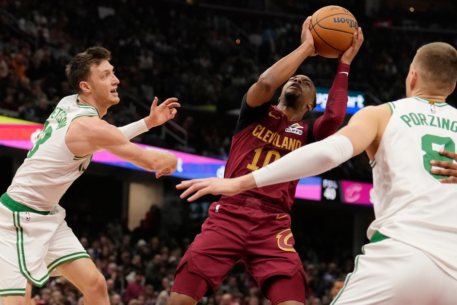 Cleveland Cavaliers guard Darius Garland shoots between Boston Celtics forward Drew Peterson, left, and center Kristaps Porzingis (8) in the first half of an NBA basketball game, Sunday, Dec. 1, 2024, in Cleveland. (AP Photo/Sue Ogrocki)