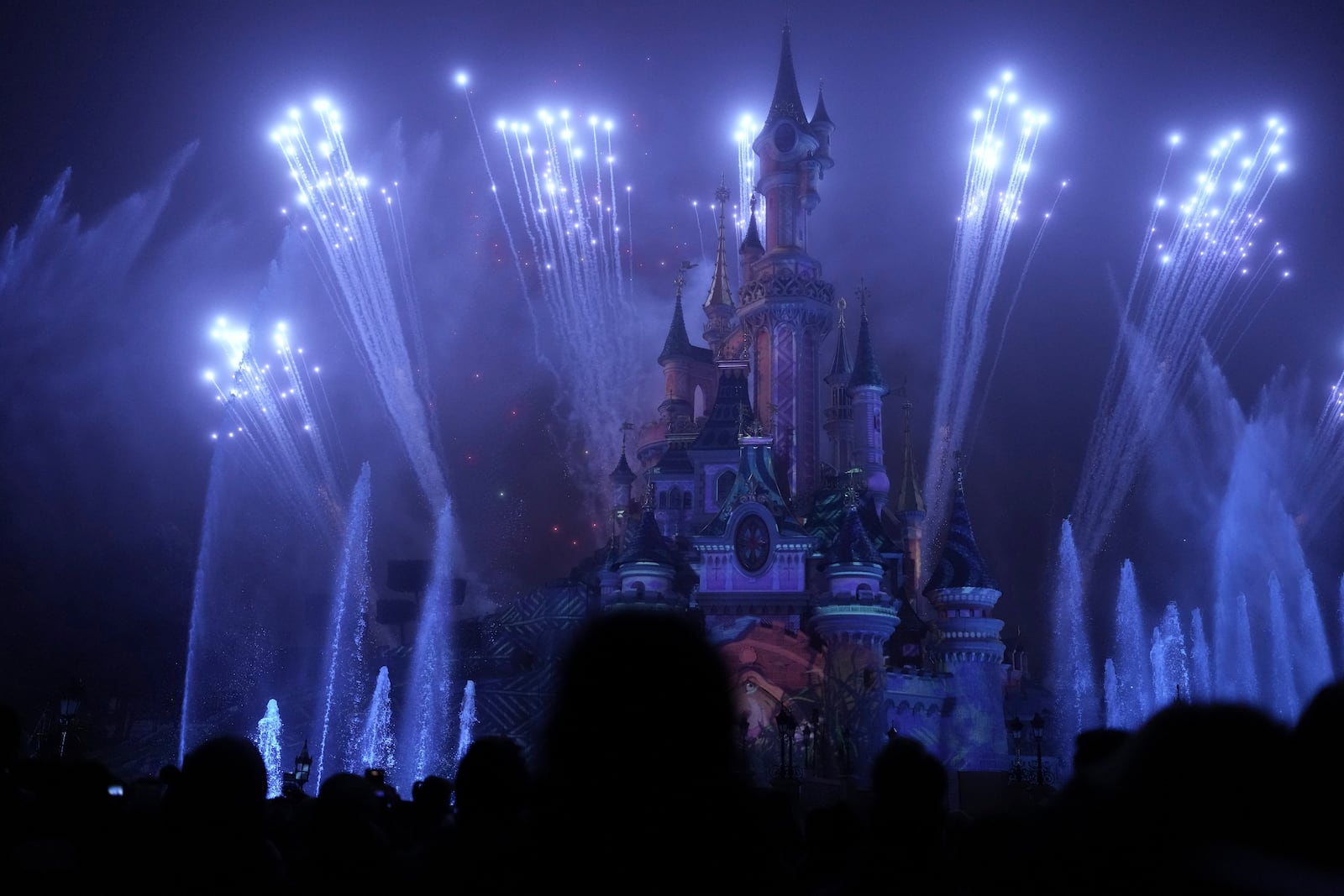 A light show is projected on the castle of Sleeping Beauty as fireworks explode in Disneyland, in Marne-la-Vallee, east of Paris, Friday Jan. 17, 2025. (AP Photo/Thibault Camus)