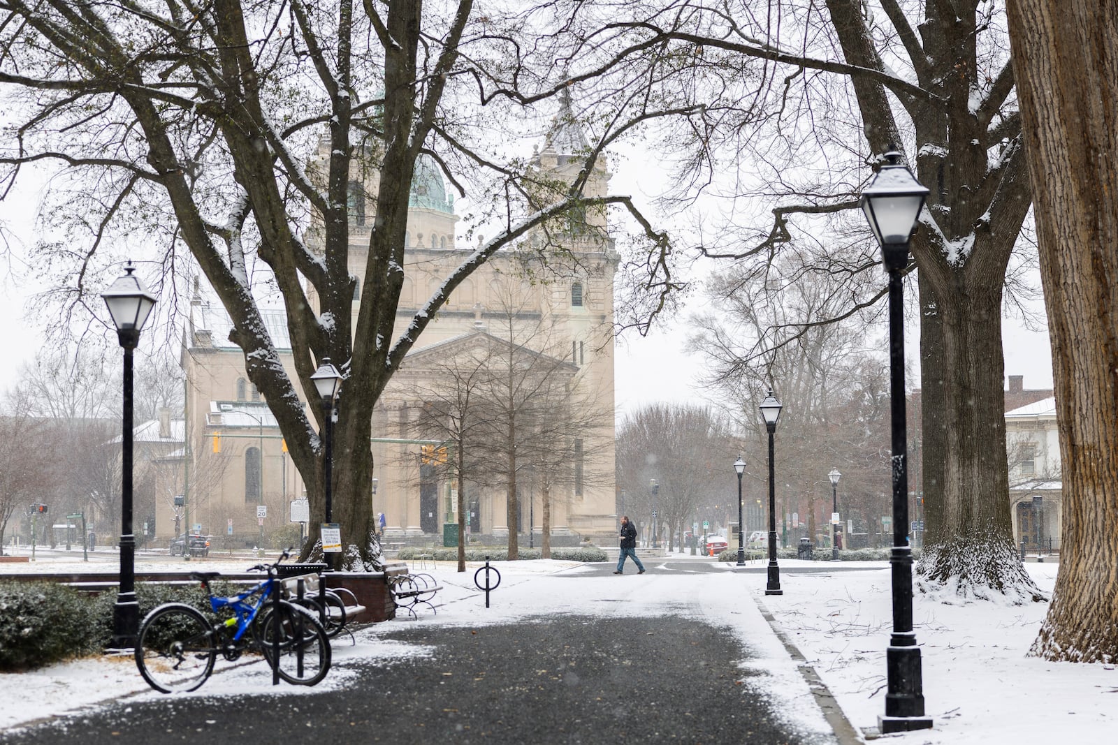 A person walks through Monroe Park as snow falls, Wednesday, Feb. 19, 2025, in Richmond, Va. (Margo Wagner/Richmond Times-Dispatch via AP)