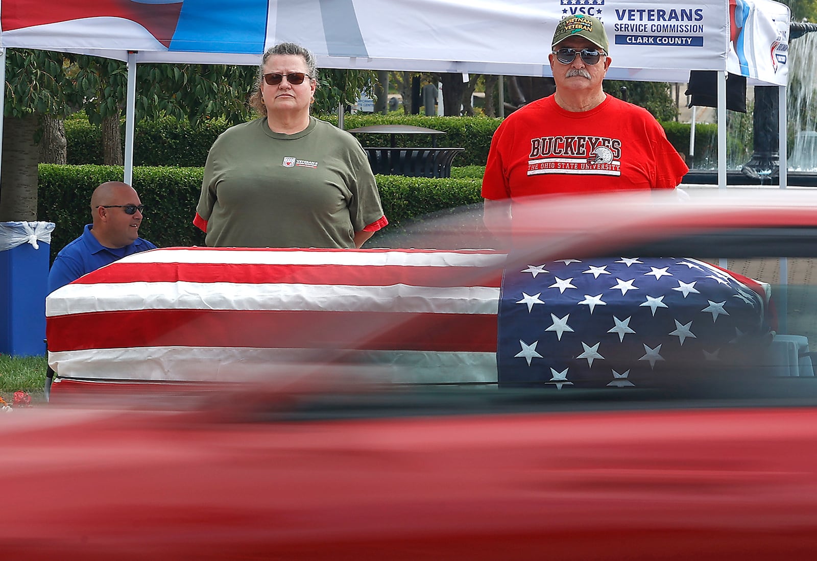 A car zooms past as Roger Tackett and his daughter, Debbie Harbaugh, stand silently over a flag draped casket at the intersection of South Fountain Avenue and High Street Saturday, Sept. 9, 2023. The annual display is called Silent Watch as is meant to bring awareness to veteran suicides. Volunteers took turns standing silently with the casket for 15-minute intervals throughout the day to draw attention to veterans in need. BILL LACKEY/STAFF