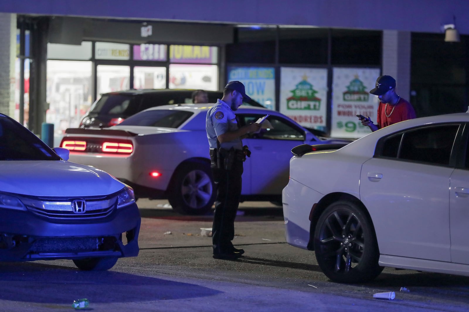 A New Orleans police officer takes a report at the scene in the Save O Lot parking lot where several people were shot and killed in New Orleans Sunday Nov. 17, 2024. (David Grunfeld/The Times-Picayune/The New Orleans Advocate via AP)