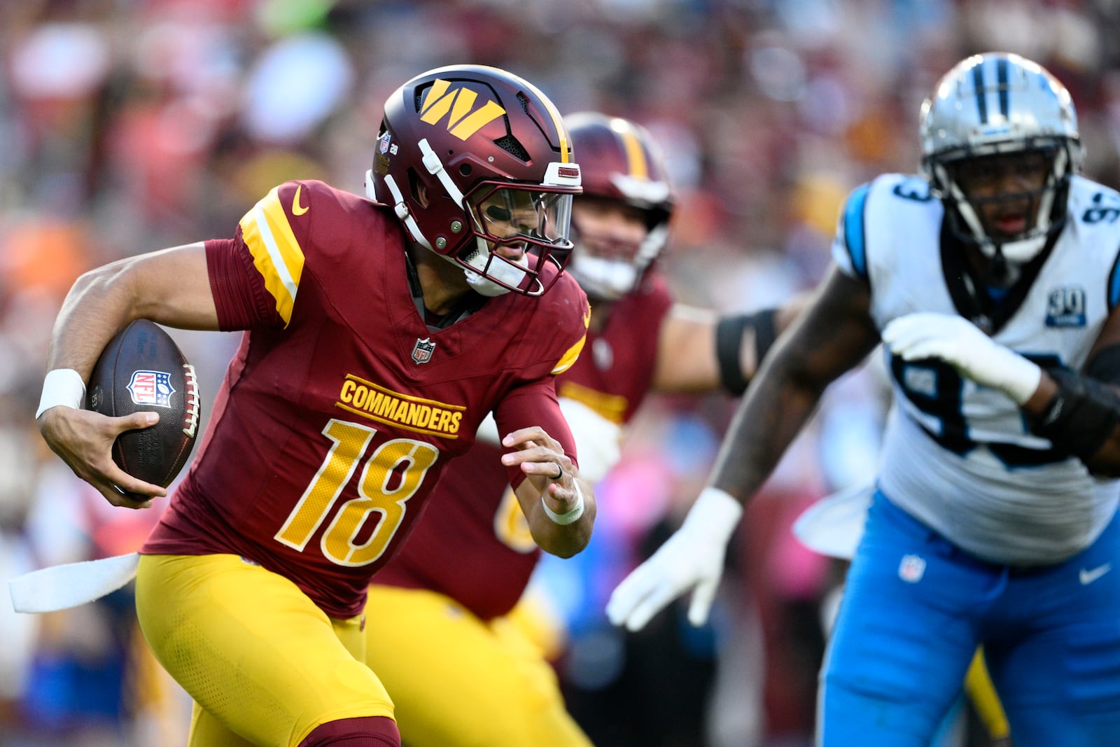 Washington Commanders quarterback Marcus Mariota (18) runs from Carolina Panthers defensive end LaBryan Ray (93) during the first half of an NFL football game, Sunday, Oct. 20, 2024, in Landover, Md. (AP Photo/Nick Wass)