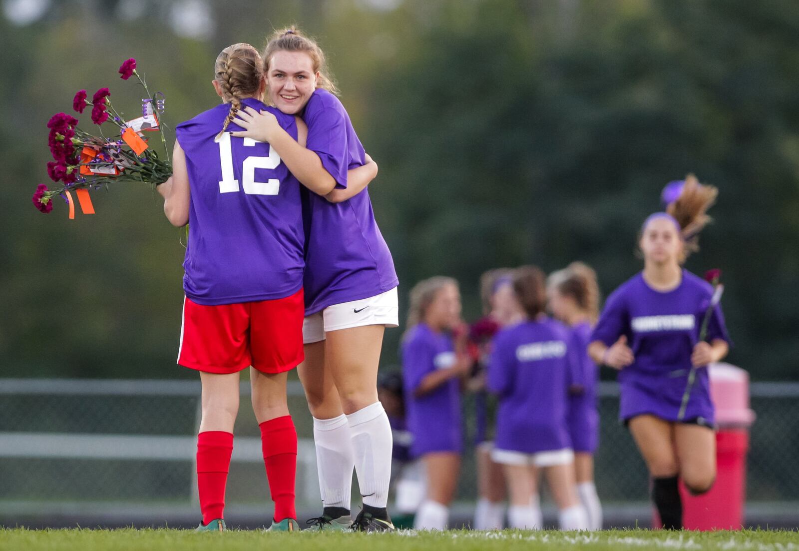 Fenwick’s Audrey Swisher (12) receives a flower and a hug from Waynesville’s Kelsey Stamm during a pregame ceremony Monday night in Middletown. Swisher, a senior, who’s been battling cystic fibrosis since she was born, saw her first game action in about a month. NICK GRAHAM/STAFF