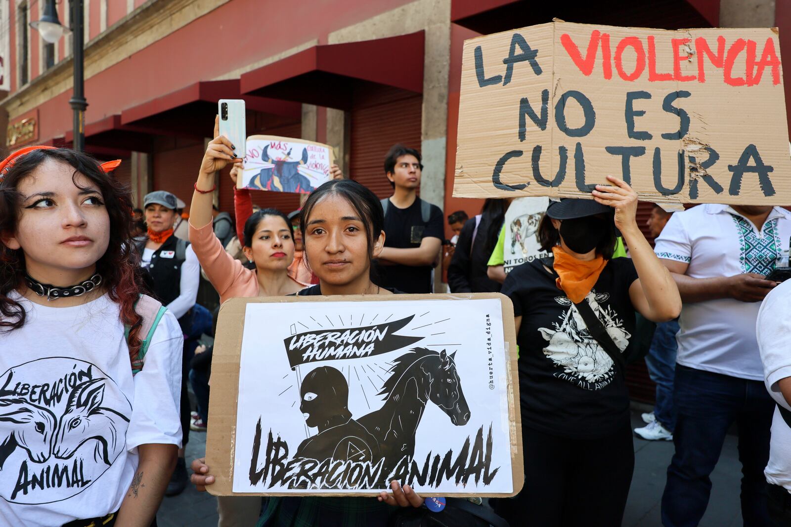 People demonstrate against bullfighting with signs that read in Spanish "Human liberation. Animal liberation," center, and "Violence is not culture," right, outside Mexico's City's Congress where lawmakers are expected to debate the continuation of bullfighting in Mexico City, Tuesday, March 18, 2025. (AP Photo/Ginnette Riquelme)