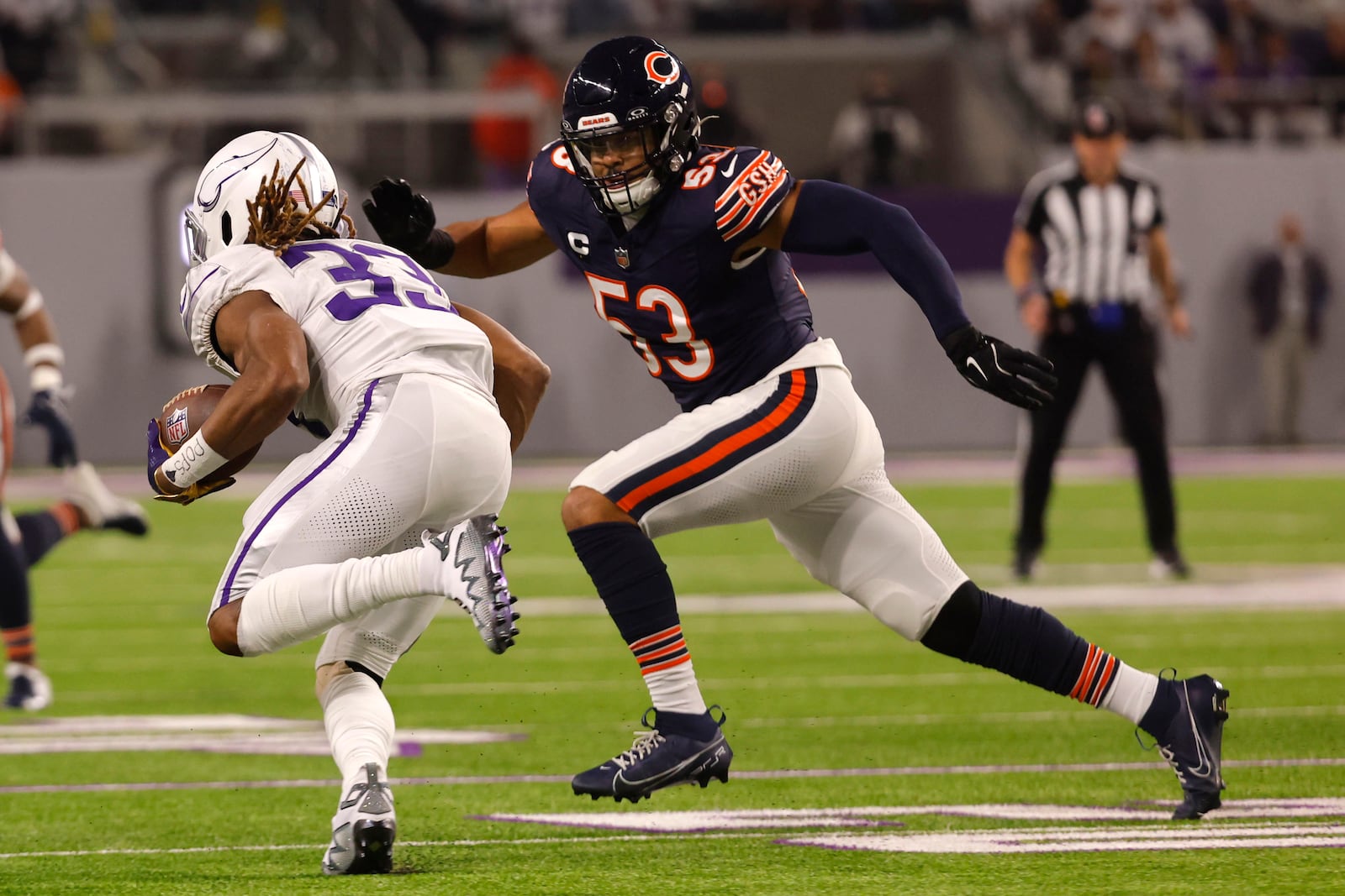 Minnesota Vikings running back Aaron Jones (33) runs from Chicago Bears linebacker T.J. Edwards (53) during the first half of an NFL football game, Monday, Dec. 16, 2024, in Minneapolis. (AP Photo/Bruce Kluckhohn)