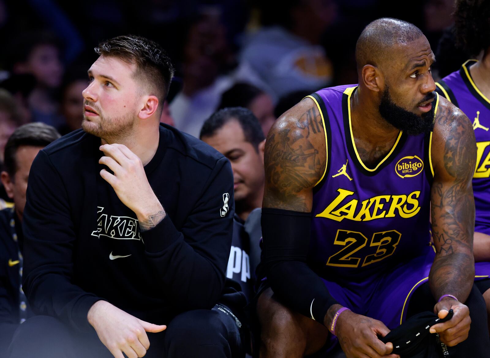 Los Angeles Lakers guard Luka Doncic, left, and forward LeBron James (23) look on from the bench during the first half of an NBA basketball game against the Golden State Warriors, Thursday, Feb. 6, 2025, in Los Angeles. (AP Photo/Kevork Djansezian)