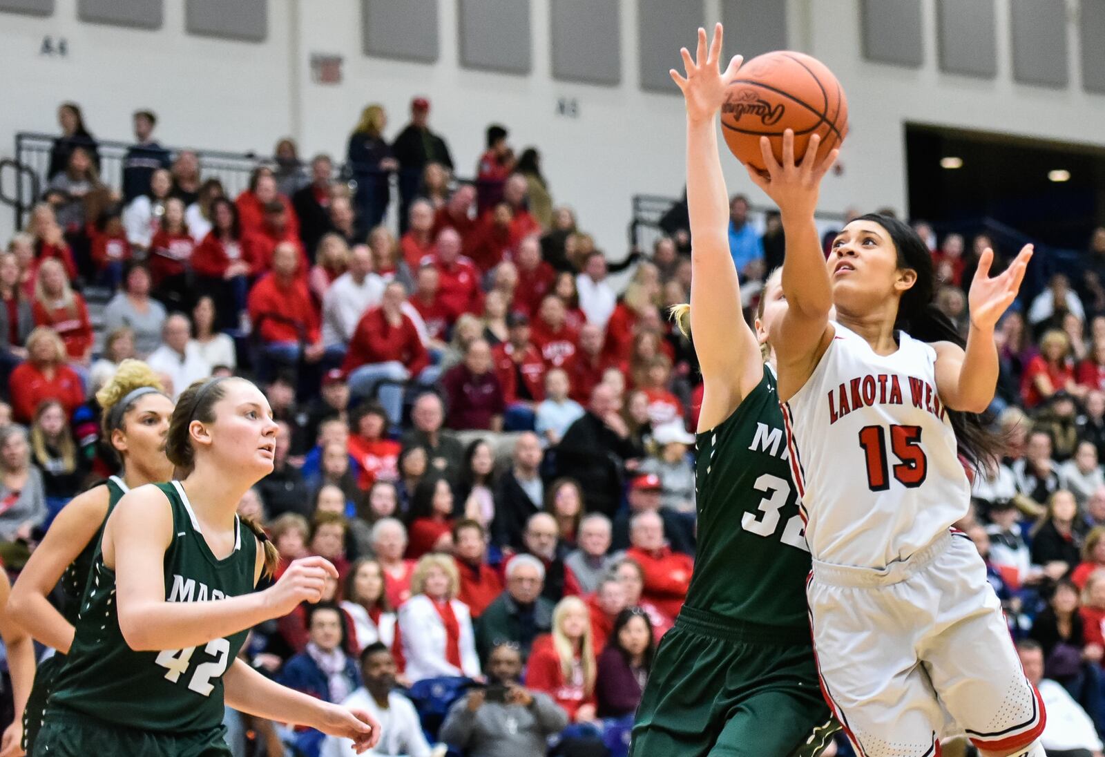 Lakota West’s Sarah Jones puts up a shot despite the defensive effort of Mason’s Sammie Puisis (32) during Saturday night’s Division I regional final at Fairmont’s Trent Arena. NICK GRAHAM/STAFF