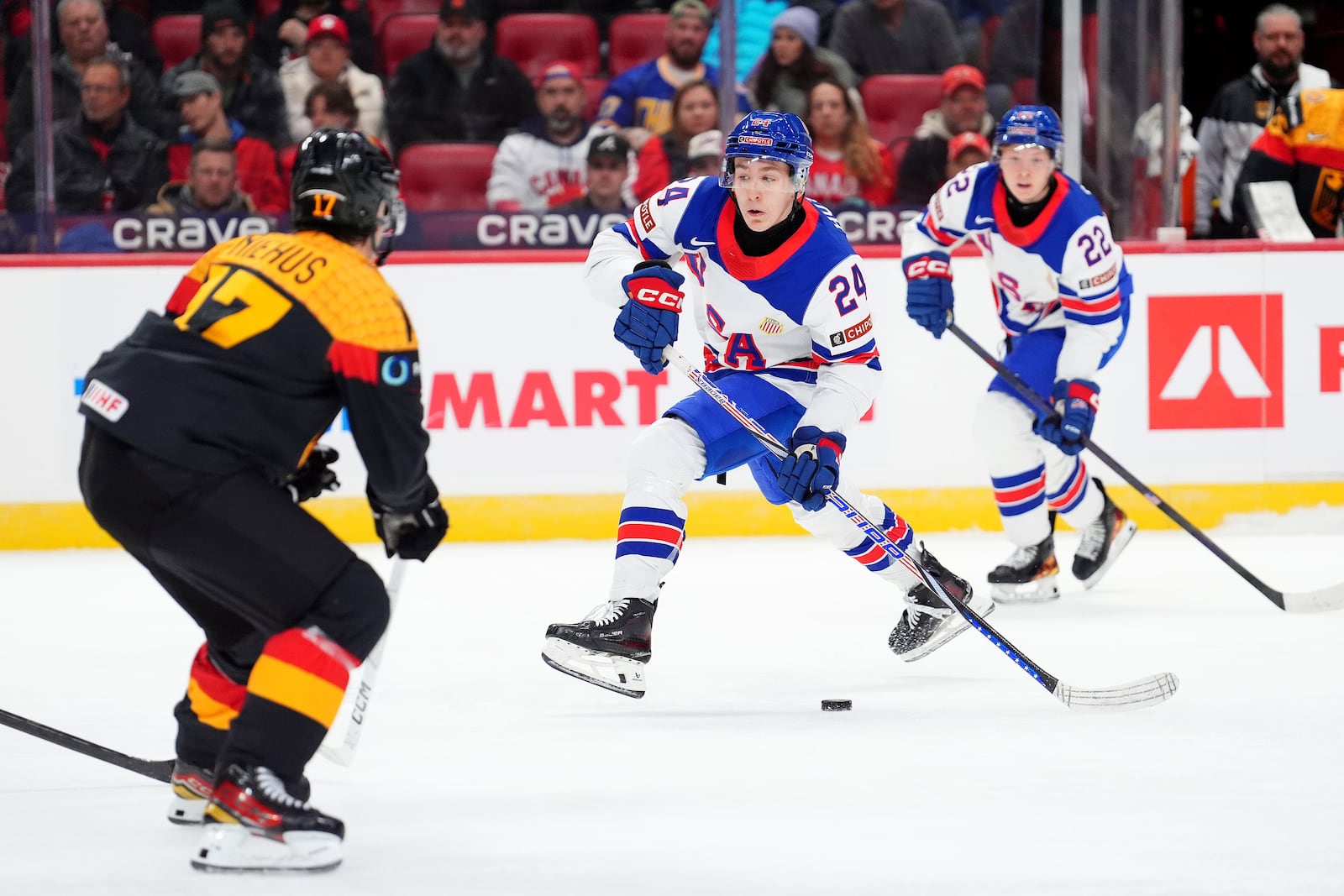 USA defenceman Cole Hutson (24) moves the puck up the ice as Germany defenceman Lua Niehaus (17) moves in the defend during third period IIHF World Junior Hockey Championship preliminary round action in Ottawa on Thursday, Dec. 26, 2024. (Sean Kilpatrick/The Canadian Press via AP)