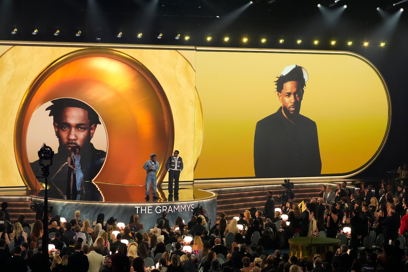 Kendrick Lamar, left, accepts the record of the year award for "Not Like Us during the 67th annual Grammy Awards on Sunday, Feb. 2, 2025, in Los Angeles. Mustard looks on from right. Miley Cyrus looks on from left.(AP Photo/Chris Pizzello)