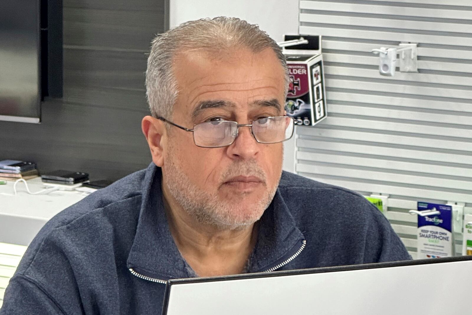 Nizam Abazid sits in his cellular shop in Dearborn, Mich., Tuesday, Dec. 10, 2024. (AP Photo/Corey Williams)