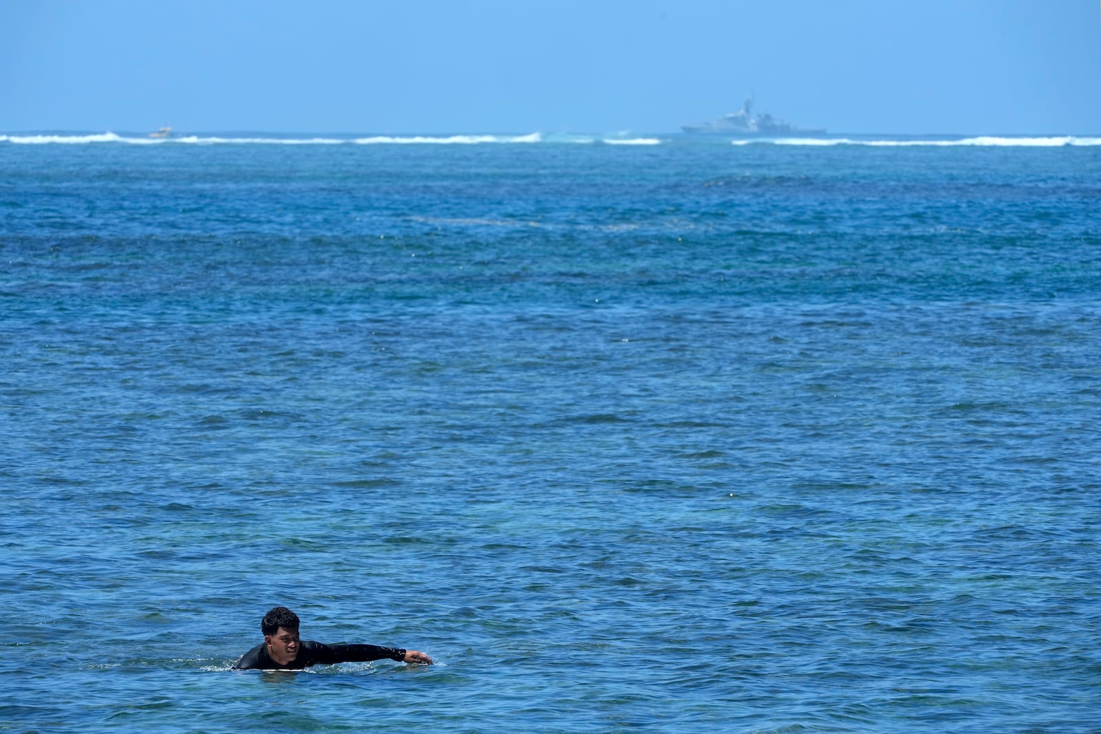 Michael Malae paddles into shore after surfing at Sima PJ Beach Fale resort in the village of Tafitoala, Samoa, on Monday, Oct. 21, 2024, near where a New Zealand navy ship ran aground and sank on Oct. 6. (AP Photo/Rick Rycroft)