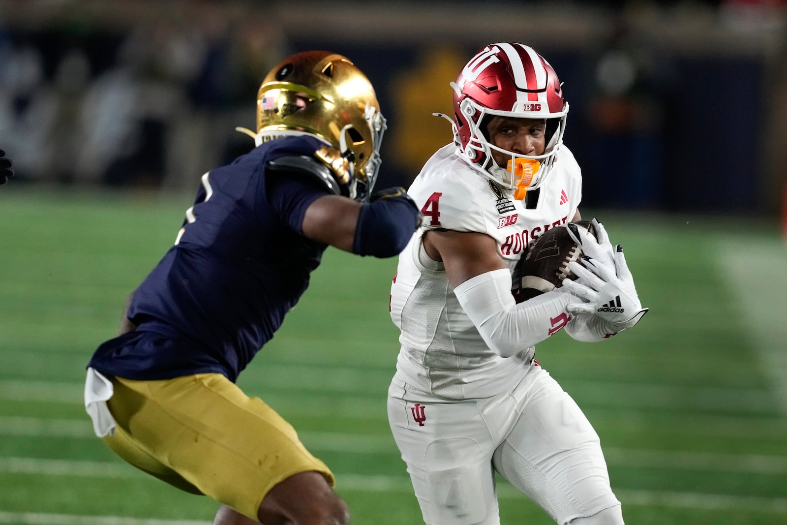 Indiana wide receiver Myles Price (4) protects the ball from Notre Dame safety Jordan Clark (1) during the first half in the first round of the NCAA College Football Playoff, Friday, Dec. 20, 2024, in South Bend, Ind. (AP Photo/Darron Cummings)