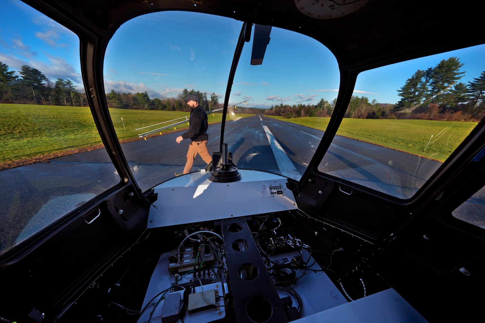 With communications and control components installed where a pilot would sit, Brett Worden, production manager at Rotor Technologies, carries a spray boom following a test flight of an unmanned semi-autonomous helicopter at Intervale Airport, Monday, Nov. 11, 2024, in Henniker, N.H. (AP Photo/Charles Krupa)