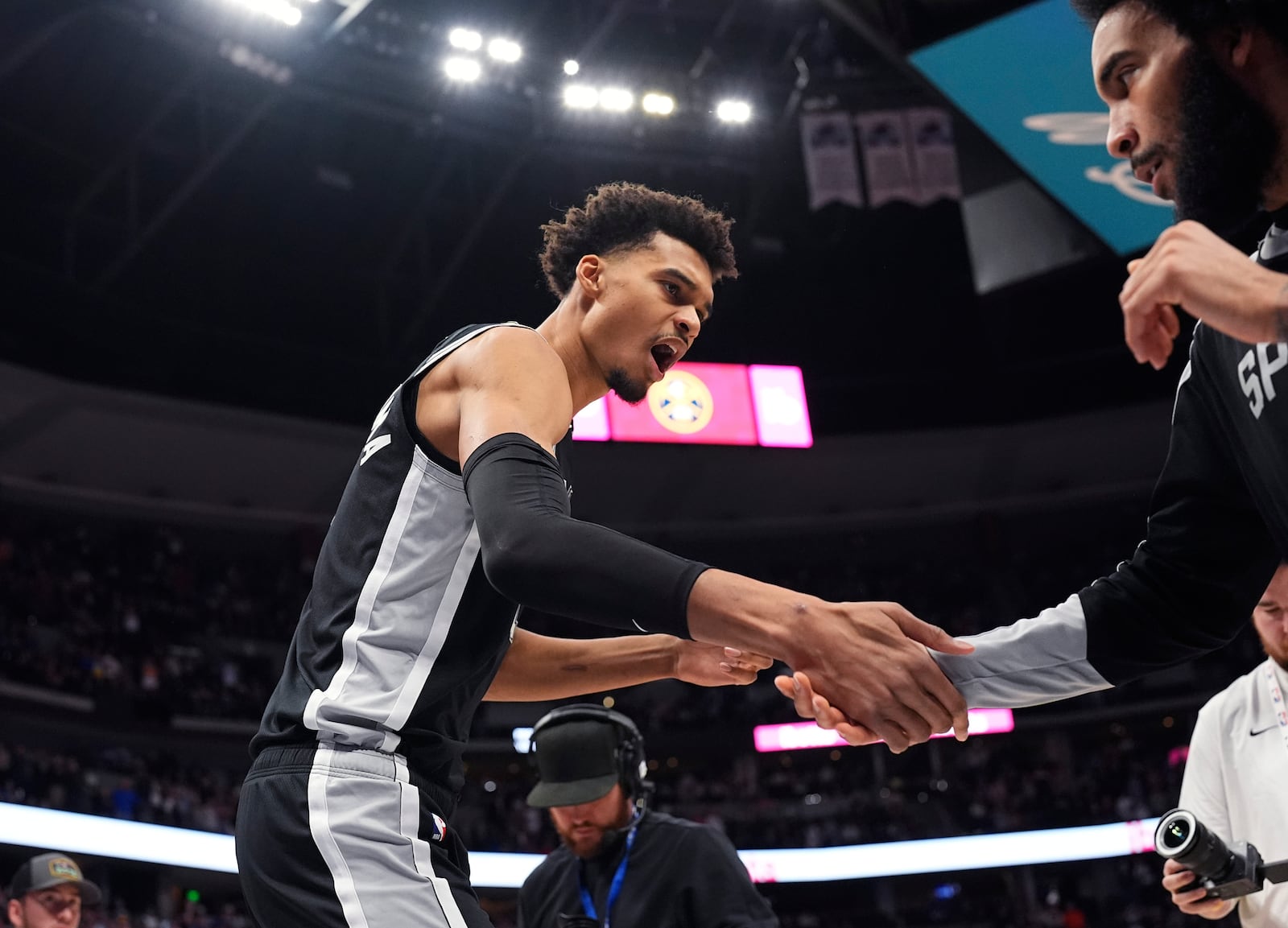 San Antonio Spurs center Victor Wembanyama, left, greets forward Julian Champagnie, right, while taking the court for an NBA basketball game against the Denver Nuggets, Friday, Jan. 3, 2025, in Denver. (AP Photo/David Zalubowski)