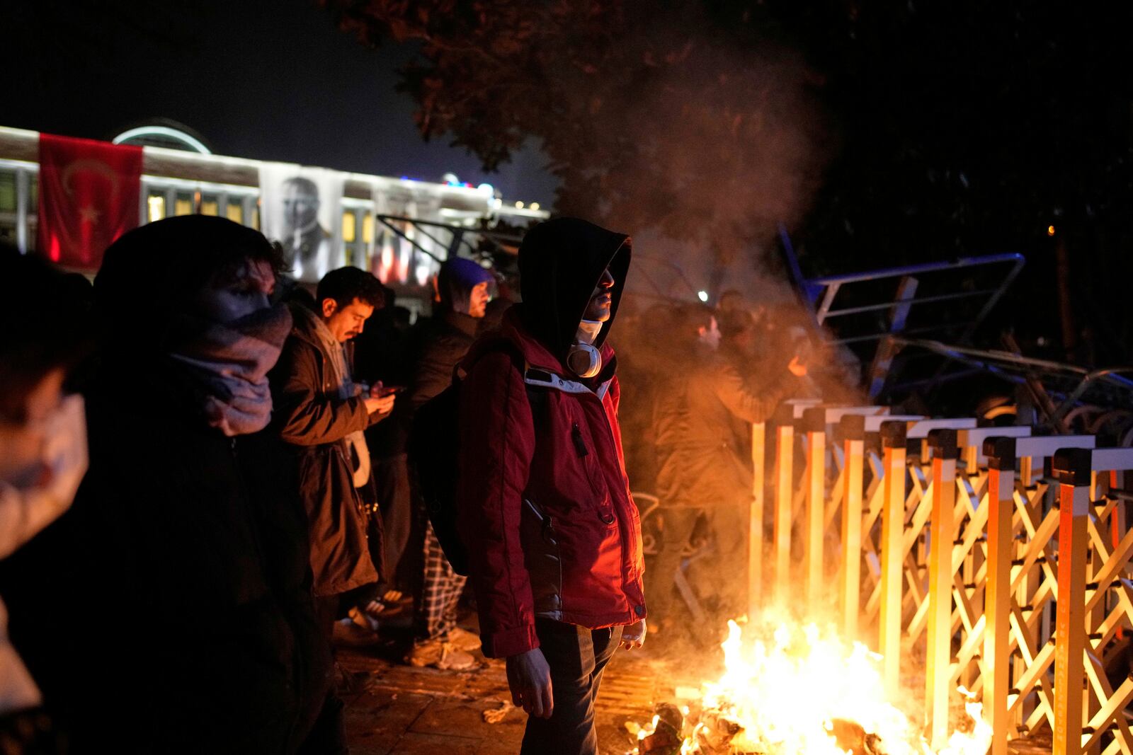 Protesters stand next to a fire during clashes with anti riot police during a protest against the arrest of Istanbul's Mayor Ekrem Imamoglu in Istanbul, Turkey, Friday, March 21, 2025. (AP Photo/Emrah Gurel)