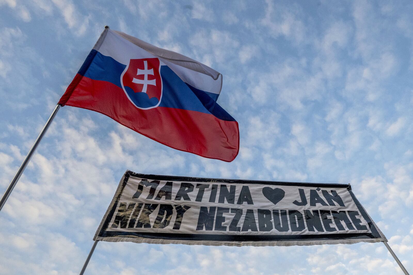 People gather in Bratislava, Slovakia on Friday Feb. 21, 2025, to mark the seventh anniversary of the slayings of an investigative journalist and his fiancee, Jan Kuciak and Martina Kusnirova. Banner reads: "Martina and Jan: We will never forget". (Vaclav Salek/CTK via AP)