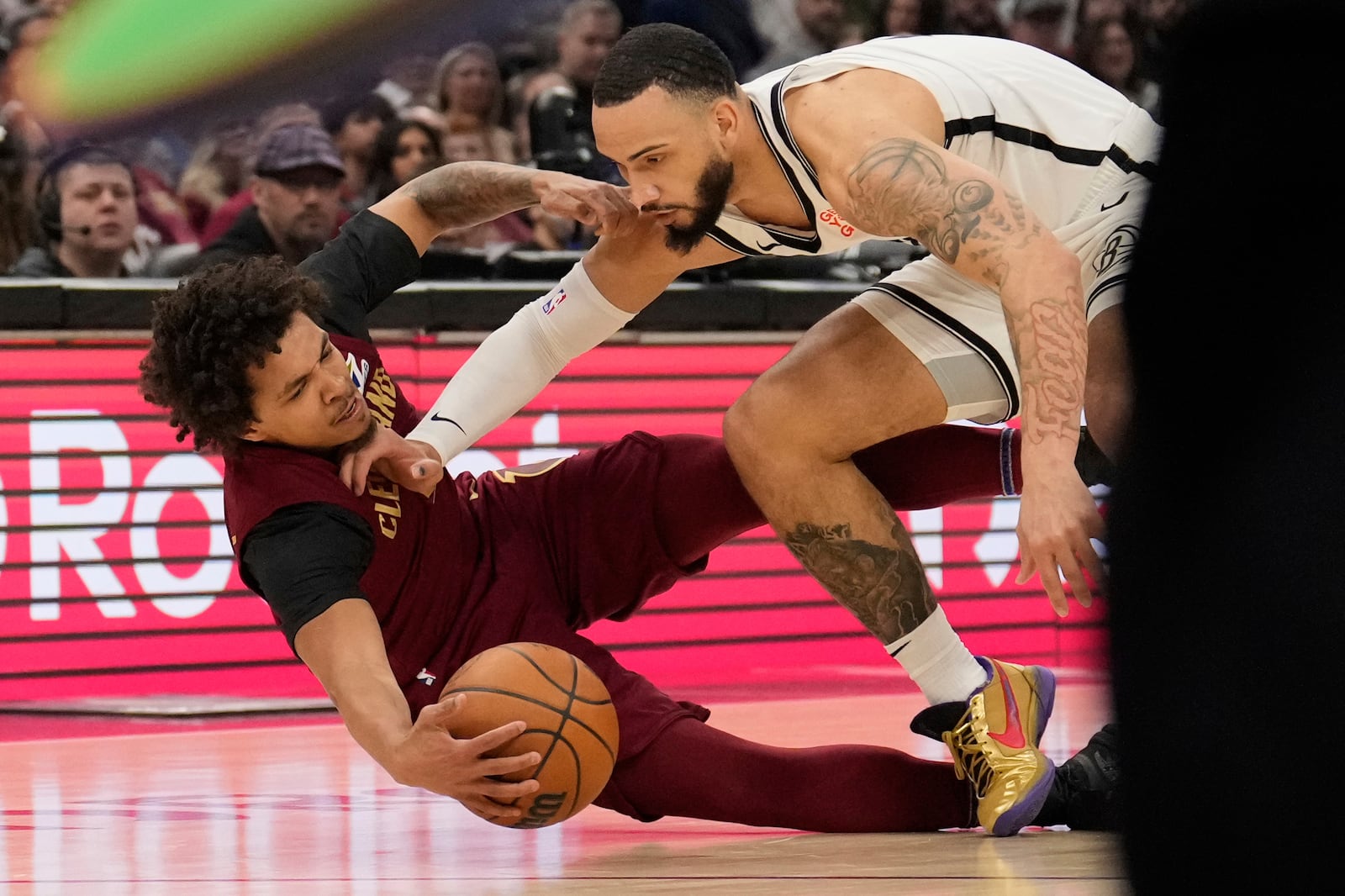 Cleveland Cavaliers guard Craig Porter Jr., left, and Brooklyn Nets forward Tyrese Martin, right, dive for the ball in the first half of an NBA basketball game Tuesday, March 11, 2025, in Cleveland. (AP Photo/Sue Ogrocki)