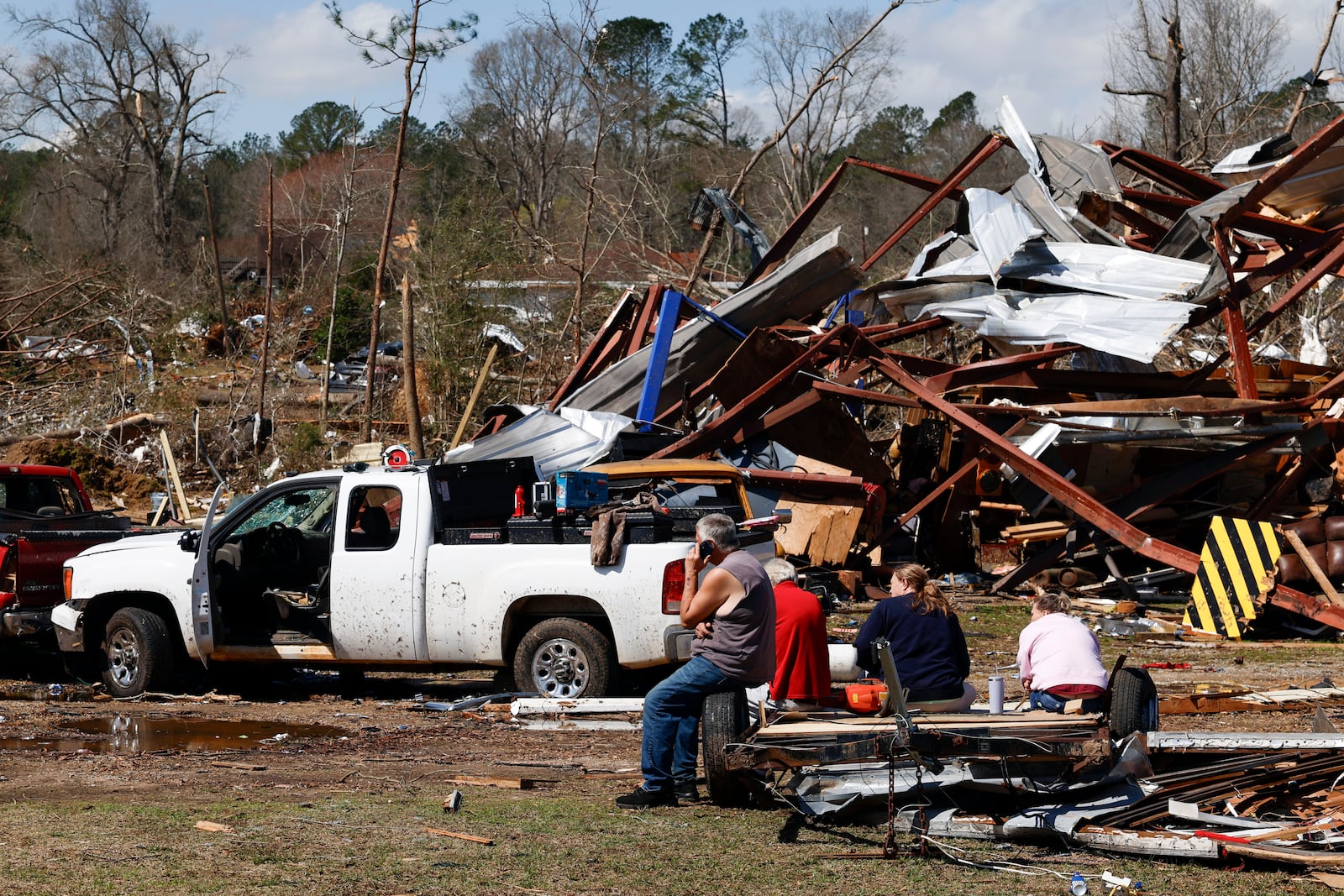 Friends and family members take a break as they search for belongings in the damage after a tornado passed through the area, Sunday, March 16, 2025, in Plantersville, Ala. (AP Photo/Butch Dill)