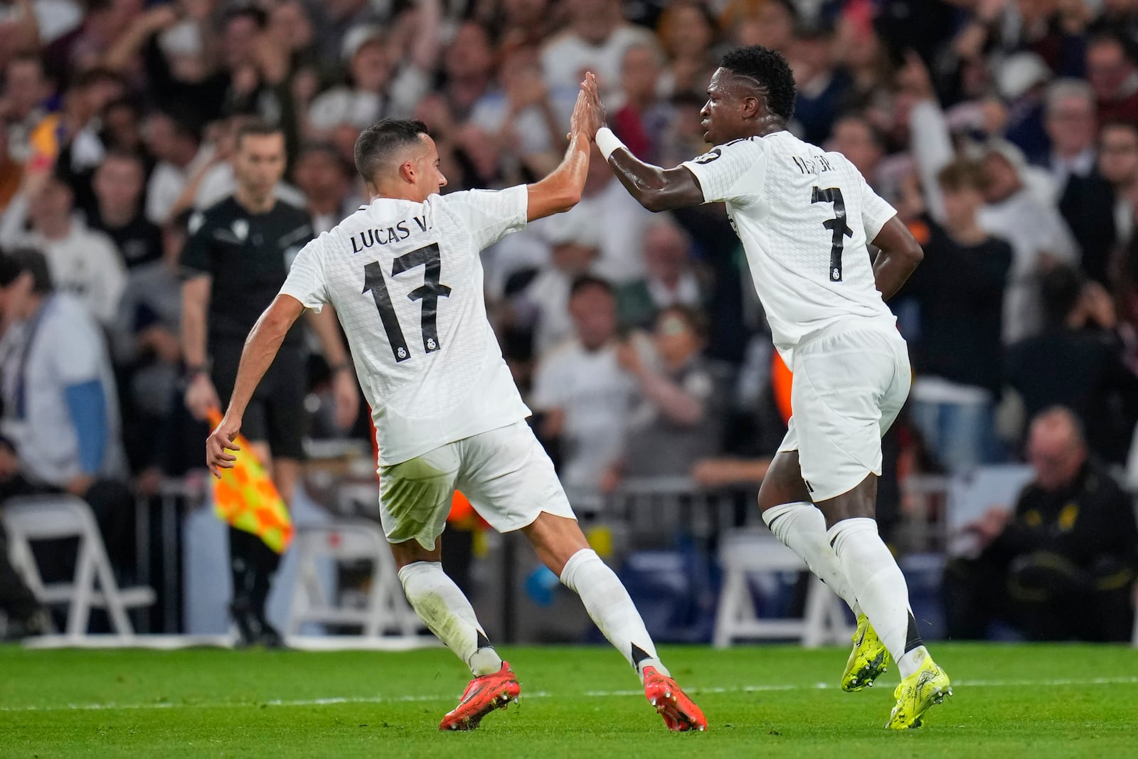 Real Madrid's Vinicius Junior, right, celebrates with teammate Lucas Vazquez after scoring his side's second goal during the Champions League opening phase soccer match between Real Madrid and Borussia Dortmund at the Santiago Bernabeu stadium in Madrid, Tuesday, Oct. 22, 2024. (AP Photo/Manu Fernandez)