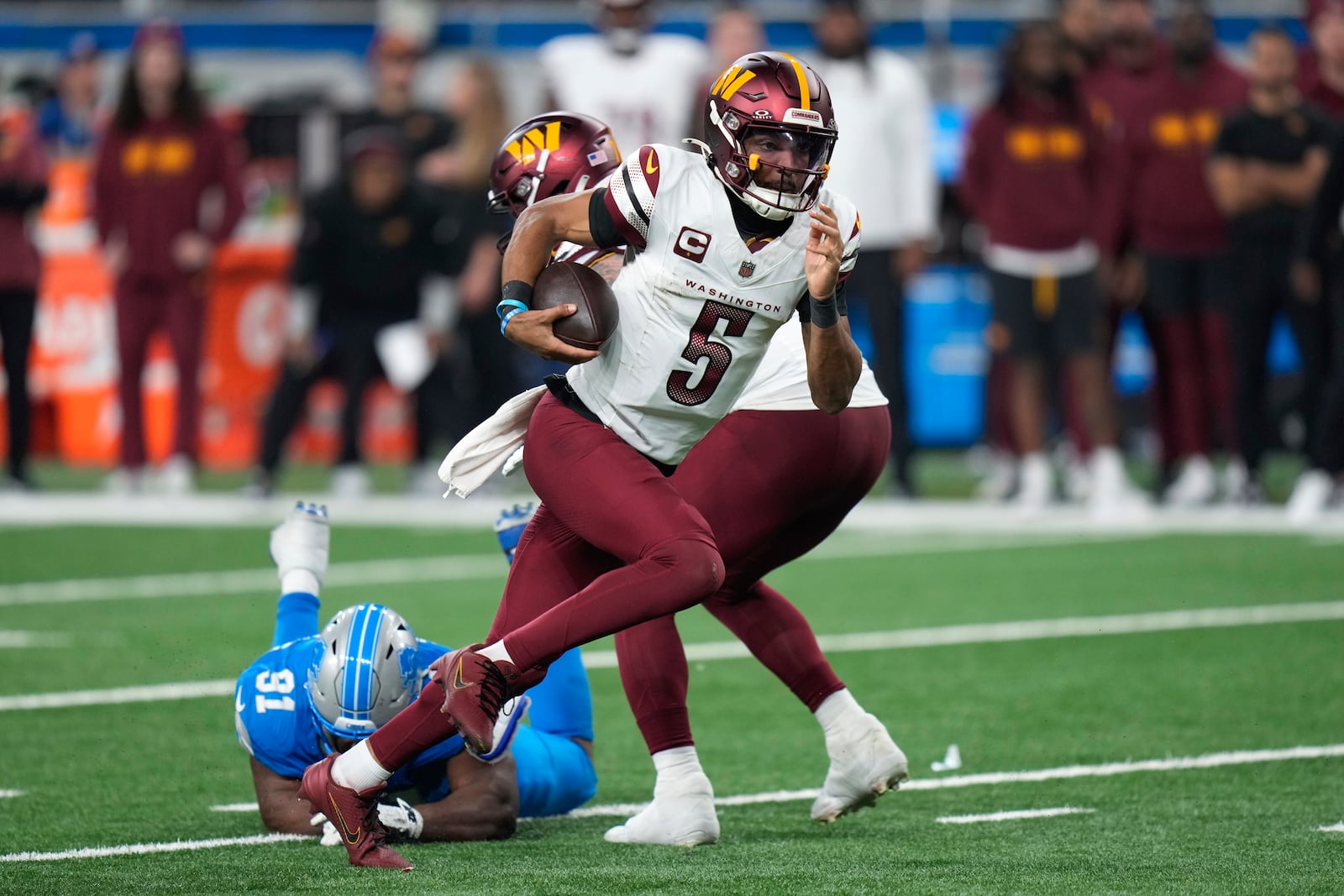 Washington Commanders quarterback Jayden Daniels (5) runs the ball past Detroit Lions defensive end Levi Onwuzurike (91) during the second half of an NFL football divisional playoff game, Saturday, Jan. 18, 2025, in Detroit. (AP Photo/Seth Wenig)